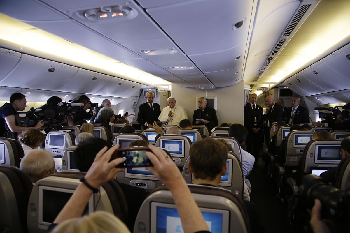 Pope Francis, second from left standing, meets the media during an airborne press conference on his journey back to Rome from Seoul, South Korea, Monday, Aug. 18, 2014. Pope Francis wrapped up his first trip to Asia on Monday by challenging Koreans - from the North and the South -  to reject the &quot;mindset of suspicion and confrontation&quot; that cloud their relations and instead find new ways to forge peace on the war-divided peninsula.