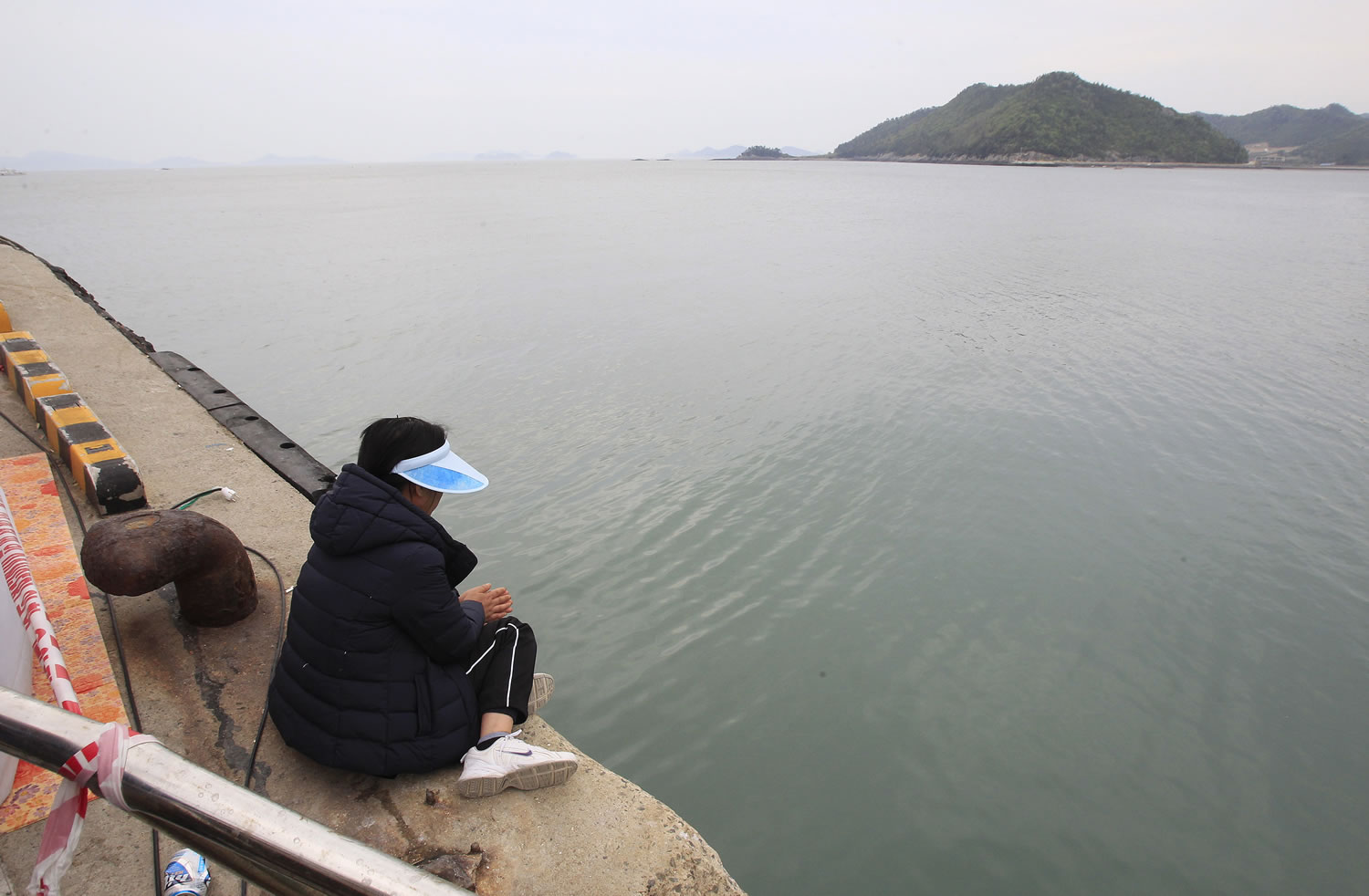 A relative of a passenger aboard the sunken Sewol ferry looks toward the sea as she awaits news on her missing loved one at a port in Jindo, South Korea, Saturday, April 26, 2014. All 15 people involved in navigating the South Korean ferry that sank and left 302 people dead or missing are now in custody after authorities on Saturday detained four more crew members, a prosecutor said.
