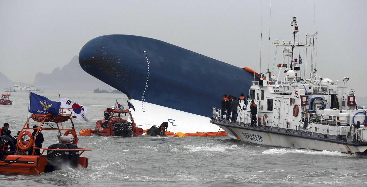 Yonhap/Associated Press
South Korean Coast Guard officers search for missing passengers from an overturned ferry today off the coast  of South Korea.