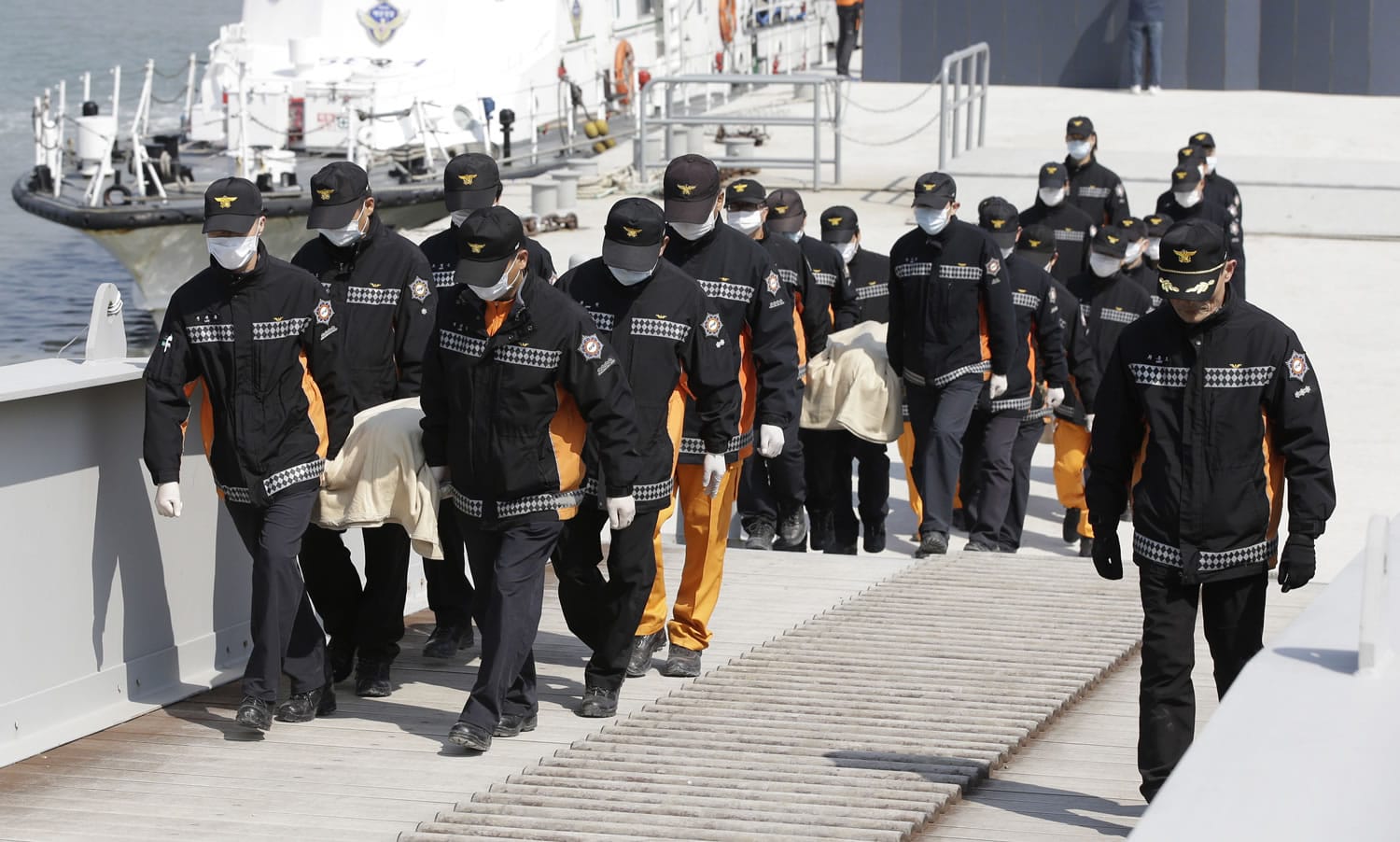 The bodies of passengers from the sunken ferry Sewol are carried by rescue workers upon their arrival today at a port in Jindo, South Korea.