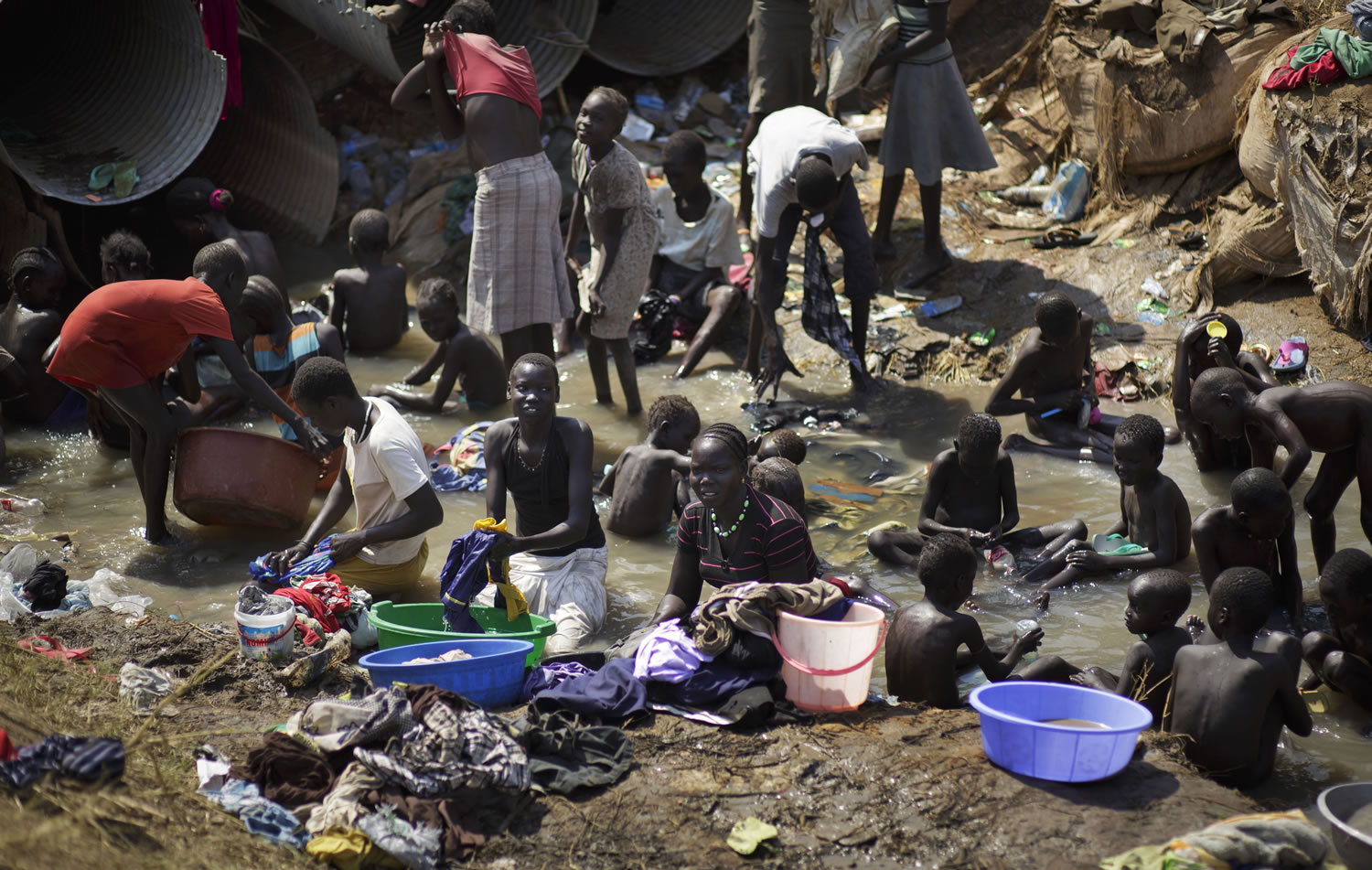 Associated Press file photos
Displaced people bathe and wash clothes Dec. 27, 2013, in a stream inside a United Nations compound in Juba, South Sudan, that had become home to thousands of refugees from fighting. One year after mass violence broke out in South Sudan, battles between government forces and rebel fighters continue, and aid officials say the international community must help residents stave off mass hunger.