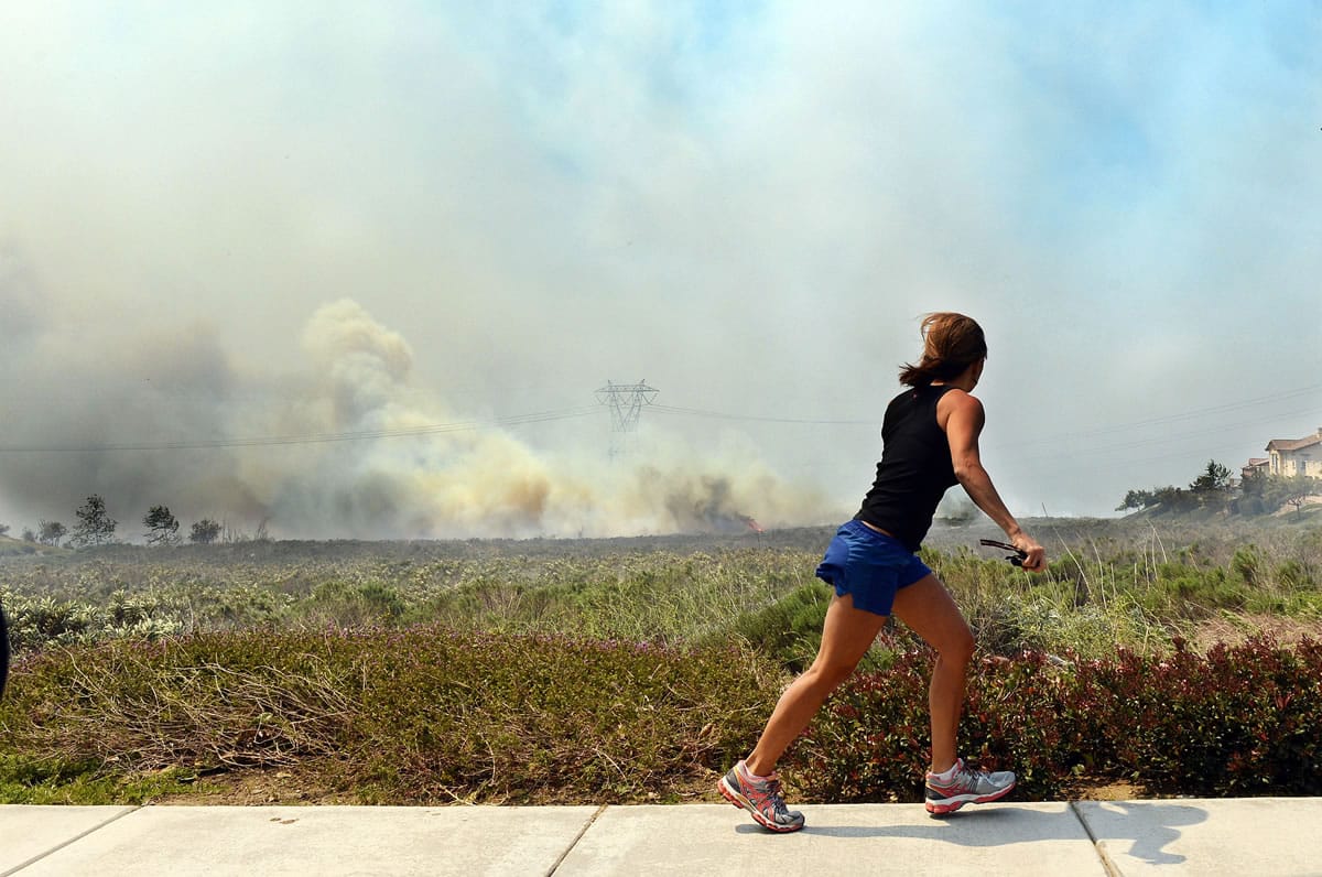 A resident talks on her phone as she watches the Etiwanda Fire in Rancho Cucamonga, Calif., on Wednesday.