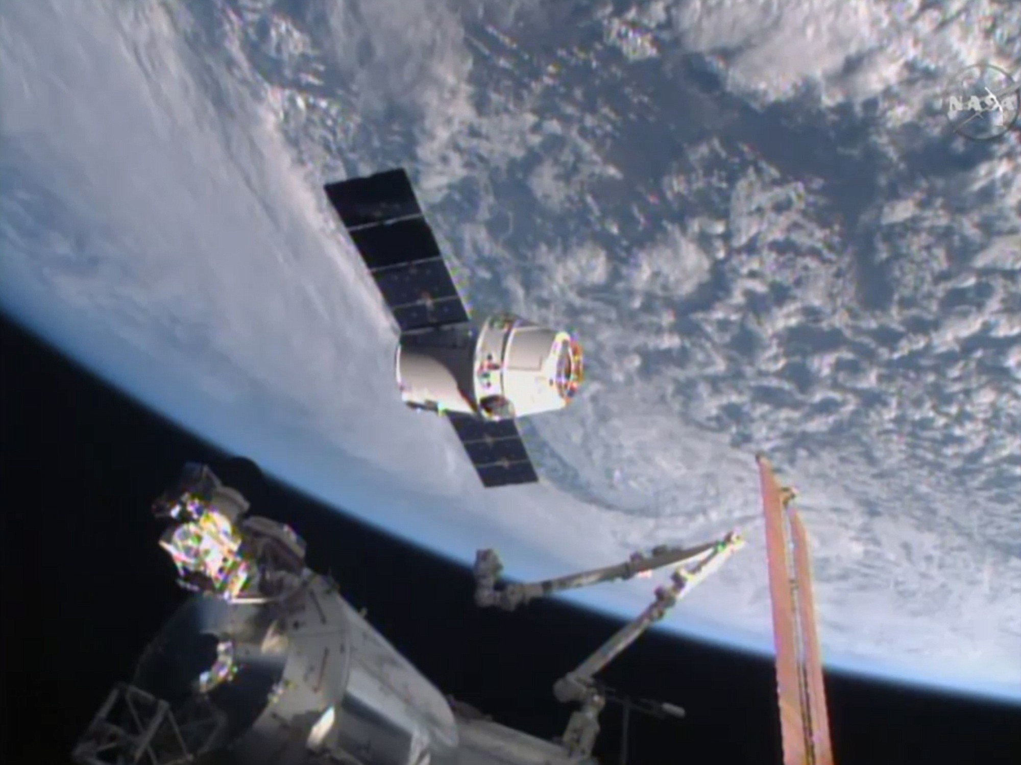 This image from NASA-TV shows the SpaceX Dragon-6 resupply capsule Friday as it holds at the grapple point, 10 meters from the International Space Station as they cross over the Asia.