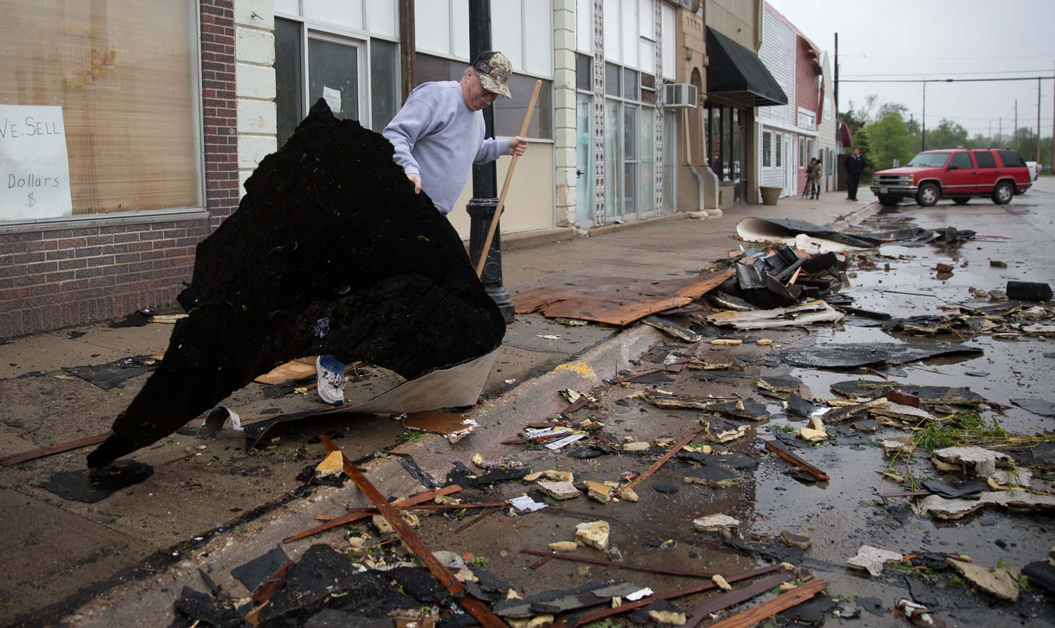 Michael Thompson clears some of the roof debris from the front of his business in Sutton Neb., on Monday.