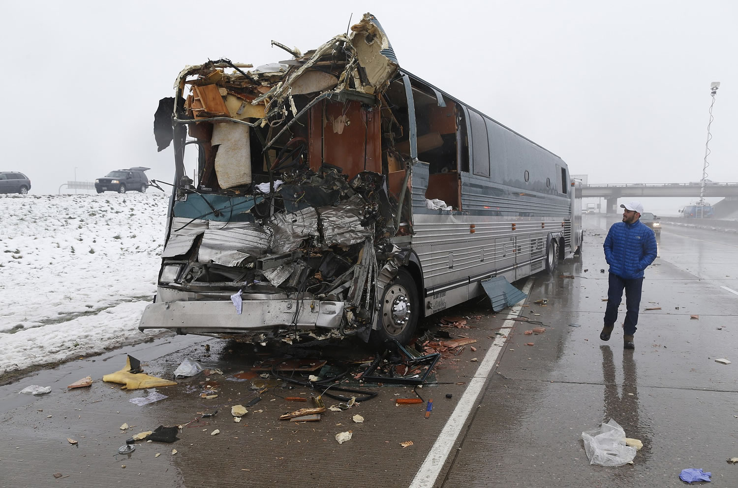 A television reporter looks over a tour bus involved in an accident with a tractor-trailer Friday in Aurora, Colo. Officials say 12 people were injured, two of them critically, in the four-vehicle wreck that shut down Interstate 70 for several hours during a spring storm packing heavy rains and fog.
