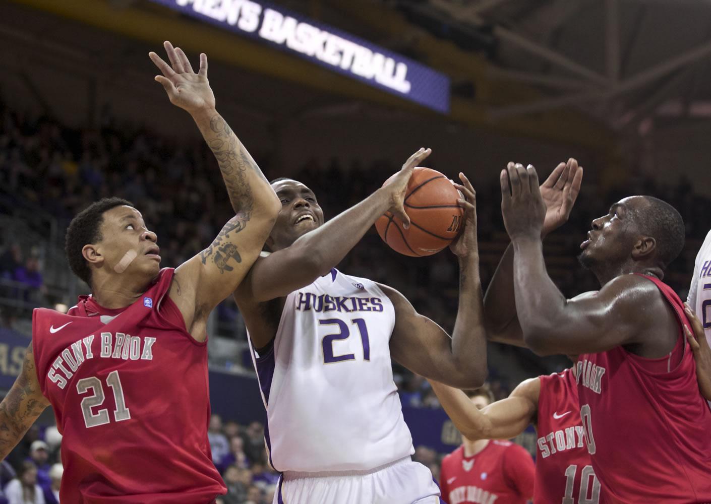 Washington's Jernard Jarreau, center, vies for a rebound with Stony Brook's Rayshaun McGrew, left, and Jameel Warney during the first half Sunday, Dec. 28, 2014, in Seattle.