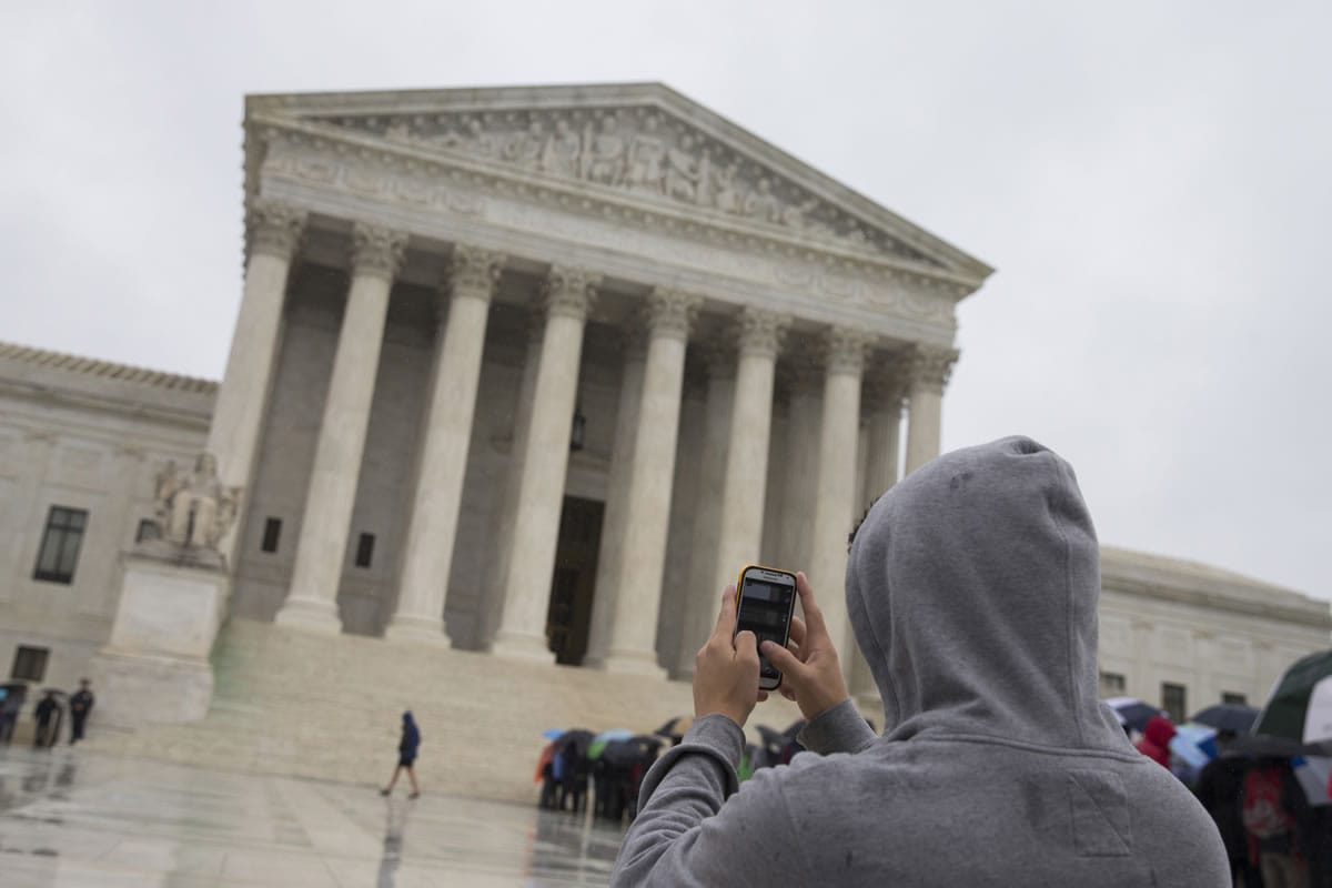 A visitor to the Supreme Court uses his cellphone to take a photo of the court in Washington on April 29. A divided Supreme Court sided with gun control groups and the Obama administration Monday, ruling that the federal ban on &quot;straw&quot; purchases of guns can be enforced even if the ultimate buyer is legally allowed to own a gun.