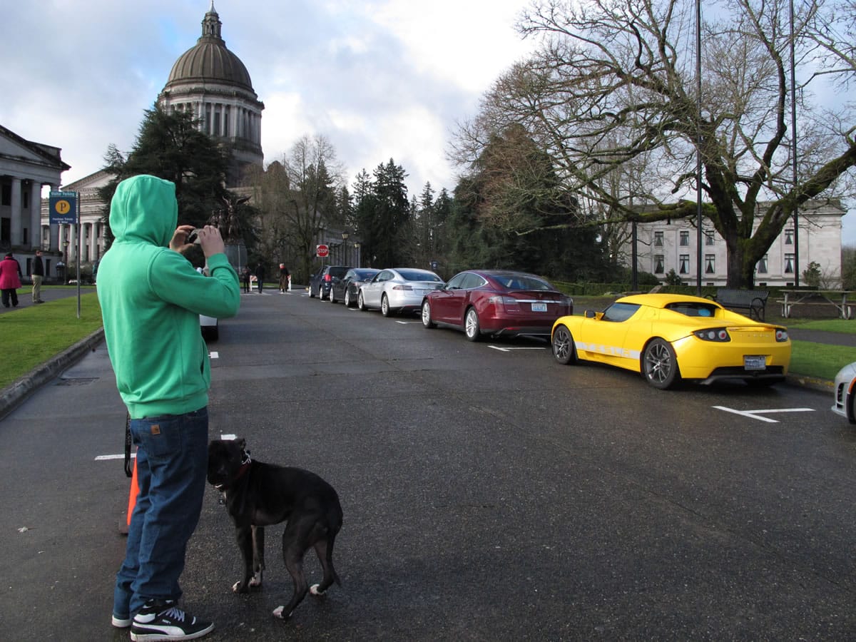 Tristan Roche of Olympia stops to take a picture of a Tesla parked near the Capitol on Monday.