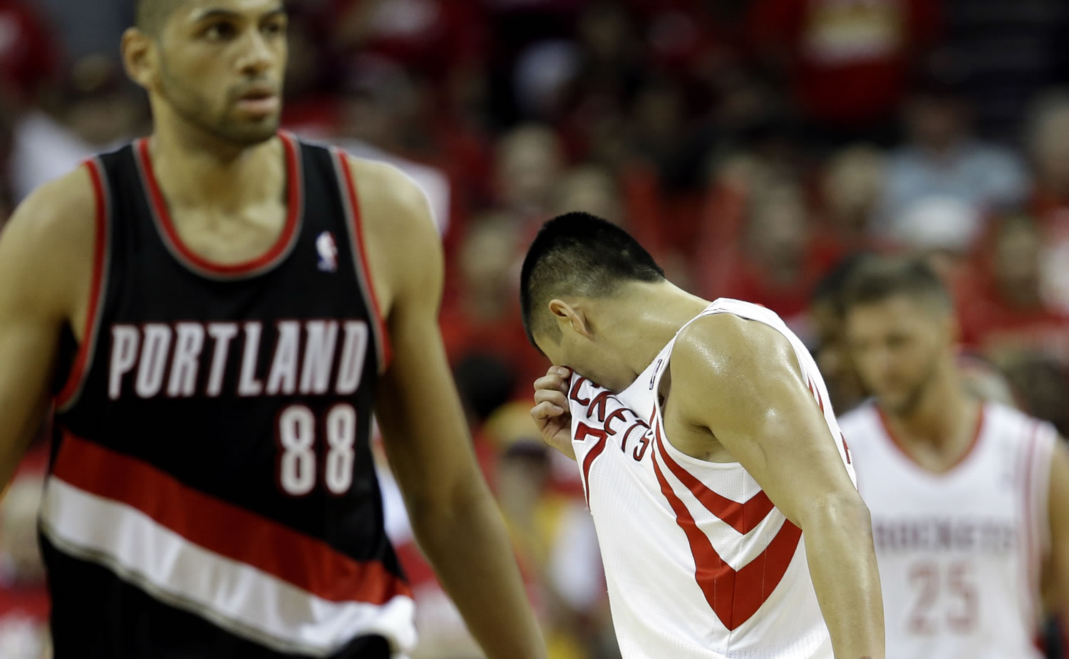 Houston Rockets' Jeremy Lin (7) wipes his face after the Rockets were called for a foul as Portland Trail Blazers' Nicolas Batum (88) walks down the court during the fourth quarter in Game 2 of an opening-round NBA basketball playoff series Wednesday, April 23, 2014, in Houston. Portland won 112-105. (AP Photo/David J.