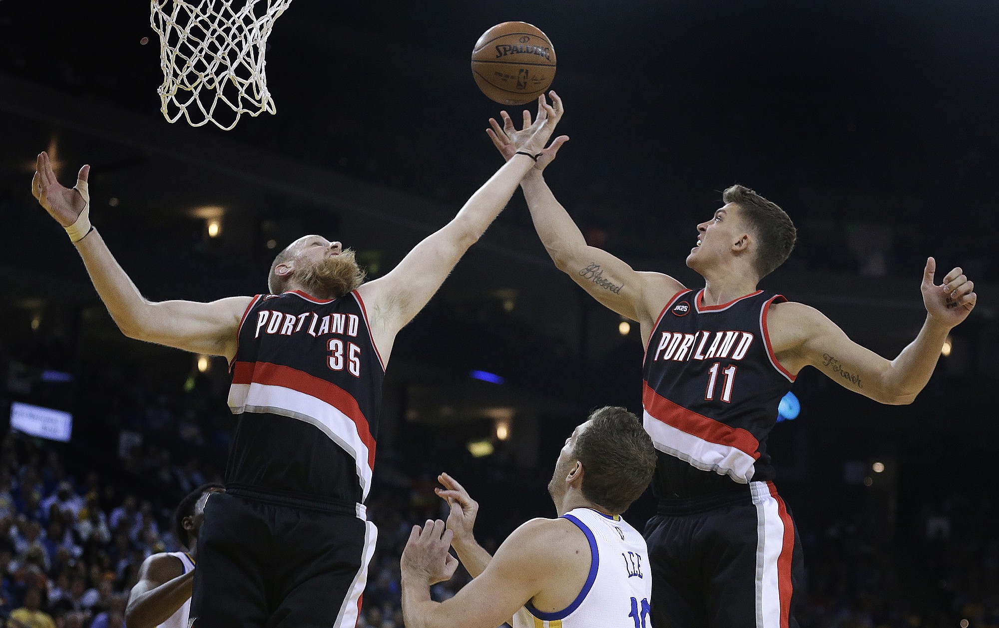 Portland Trail Blazers' Chris Kaman, left, and Meyers Leonard (11) reach for a rebound over Golden State Warriors' David Lee during the first half on Thursday, April 9, 2015, in Oakland, Calif.
