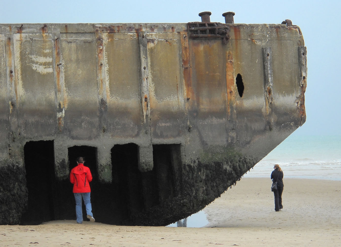A visitor inspects the remains of an artificial harbor used by Allied forces during World War II on the sand at Arromanches, France.