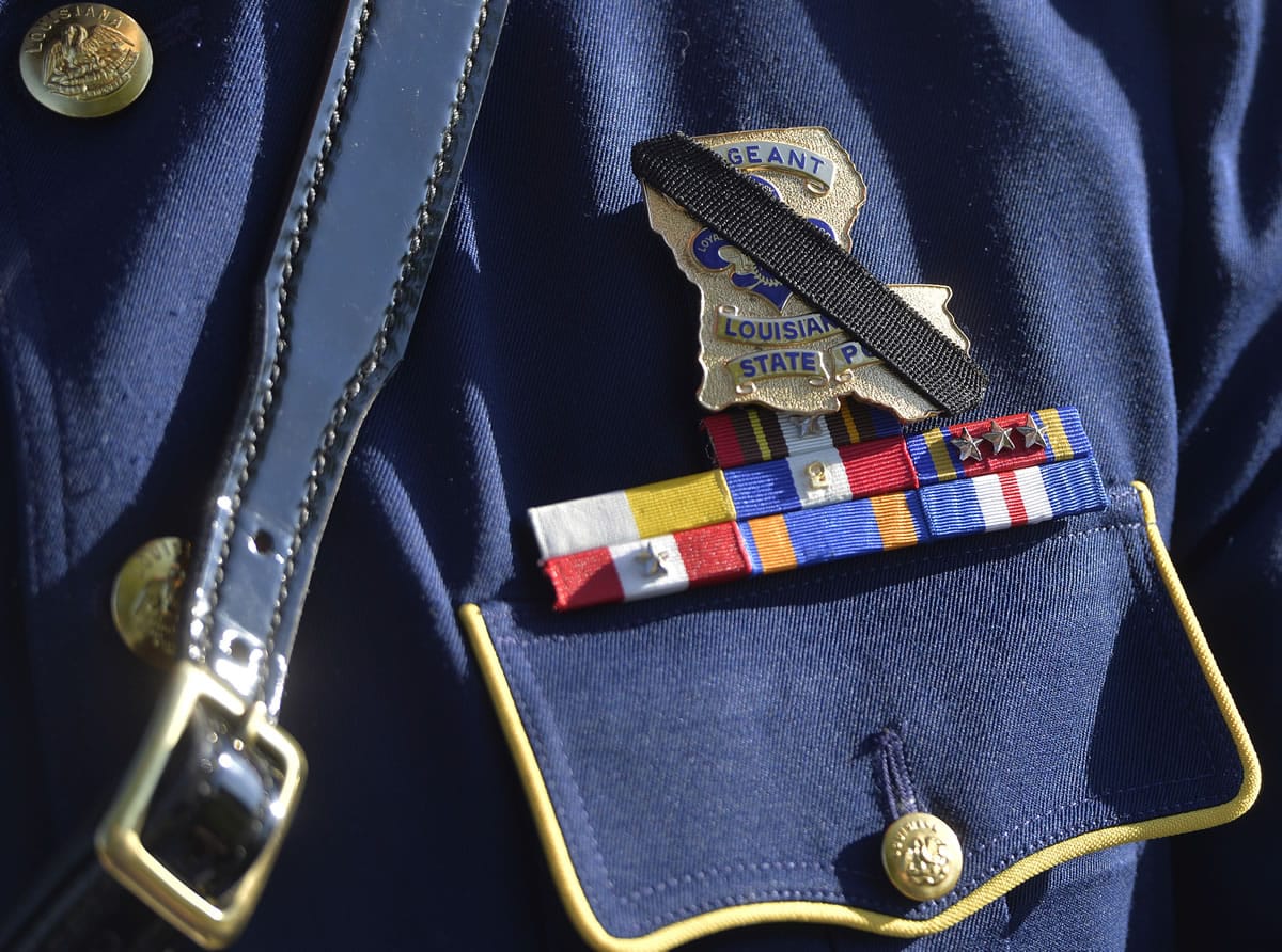 The badge of Louisiana State Police Officer Brett Travis is covered with a black band in remembrance of slain Kentucky State Police Trooper Joseph Cameron Ponder at the Severns Valley Baptist Church in Elizabethtown, Ky., Friday, Sept. 18, 2015. Ponder died Sunday night after being shot by a man he had stopped for speeding in western Kentucky.  (AP Photo/Timothy D.