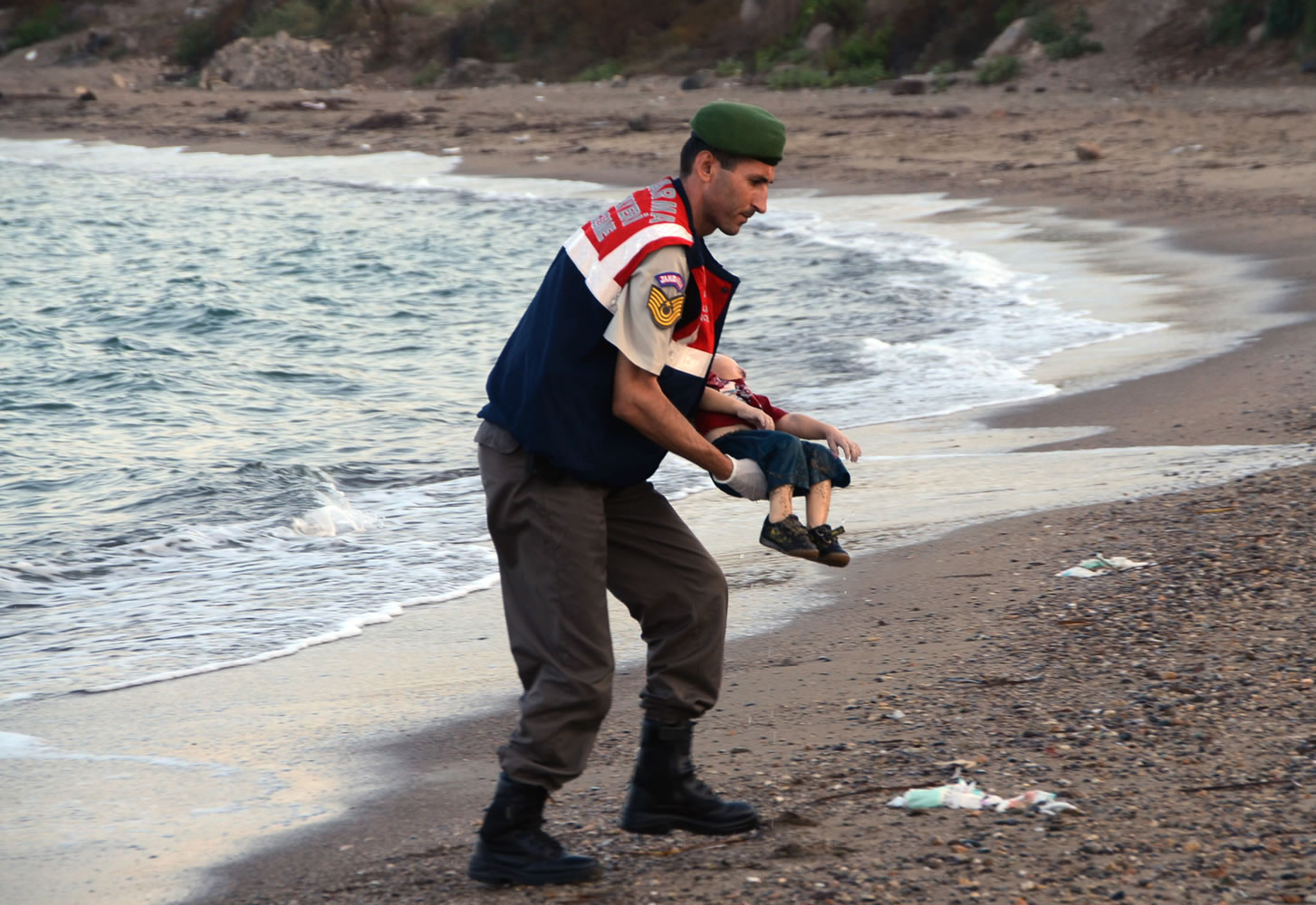 A paramilitary police officer carries the lifeless body of an unidentified migrant child, lifting it from the sea shore, near the Turkish resort of Bodrum, Turkey,  early Wednesday, Sept. 2, 2015.  A number of migrants are known to have died and some are still reported missing, after boats carrying them to the Greek island of Kos capsized.