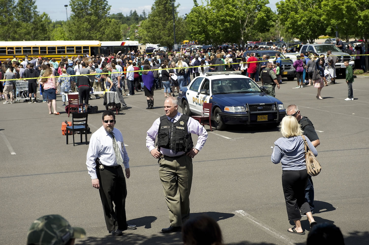 FILE - In this Tuesday, June 10, 2014, file photo, police direct parents to waiting students arriving by bus at a shopping center parking lot in Wood Village, Ore., after a shooting at Reynolds High School, in nearby Troutdale. Police in Washington state are asking the public to stop tweeting during shootings and manhunts to avoid accidentally telling the bad guys what officers are doing. Two recent incidents led the Washington State Patrol to organize the &quot;TweetSmart&quot; campaign: the search for a gunman in Canada after three officers were killed and the shooting at Reynolds High School.