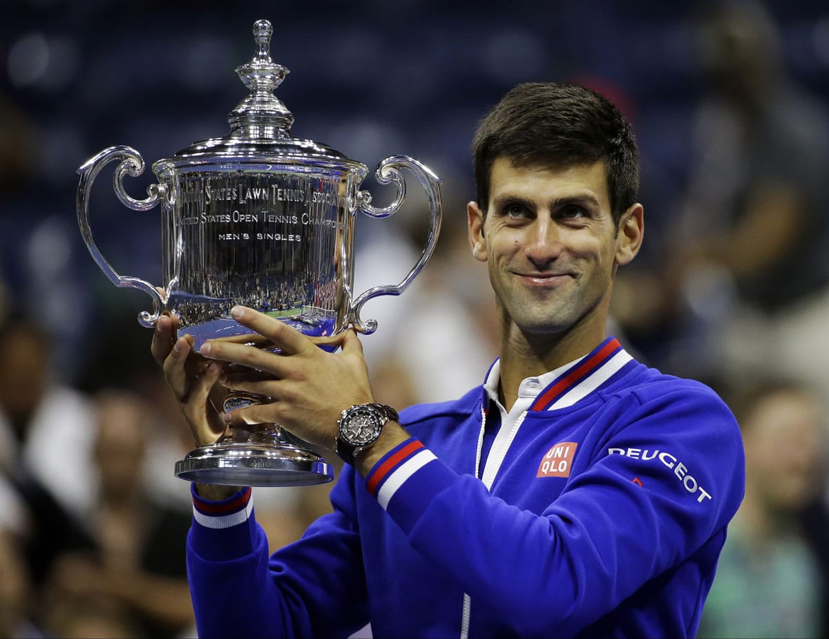 Novak Djokovic, of Serbia, holds up the championship trophy after beating Roger Federer, of Switzerland, in the men's championship match of the U.S. Open tennis tournament, Sunday, Sept. 13, 2015, in New York.