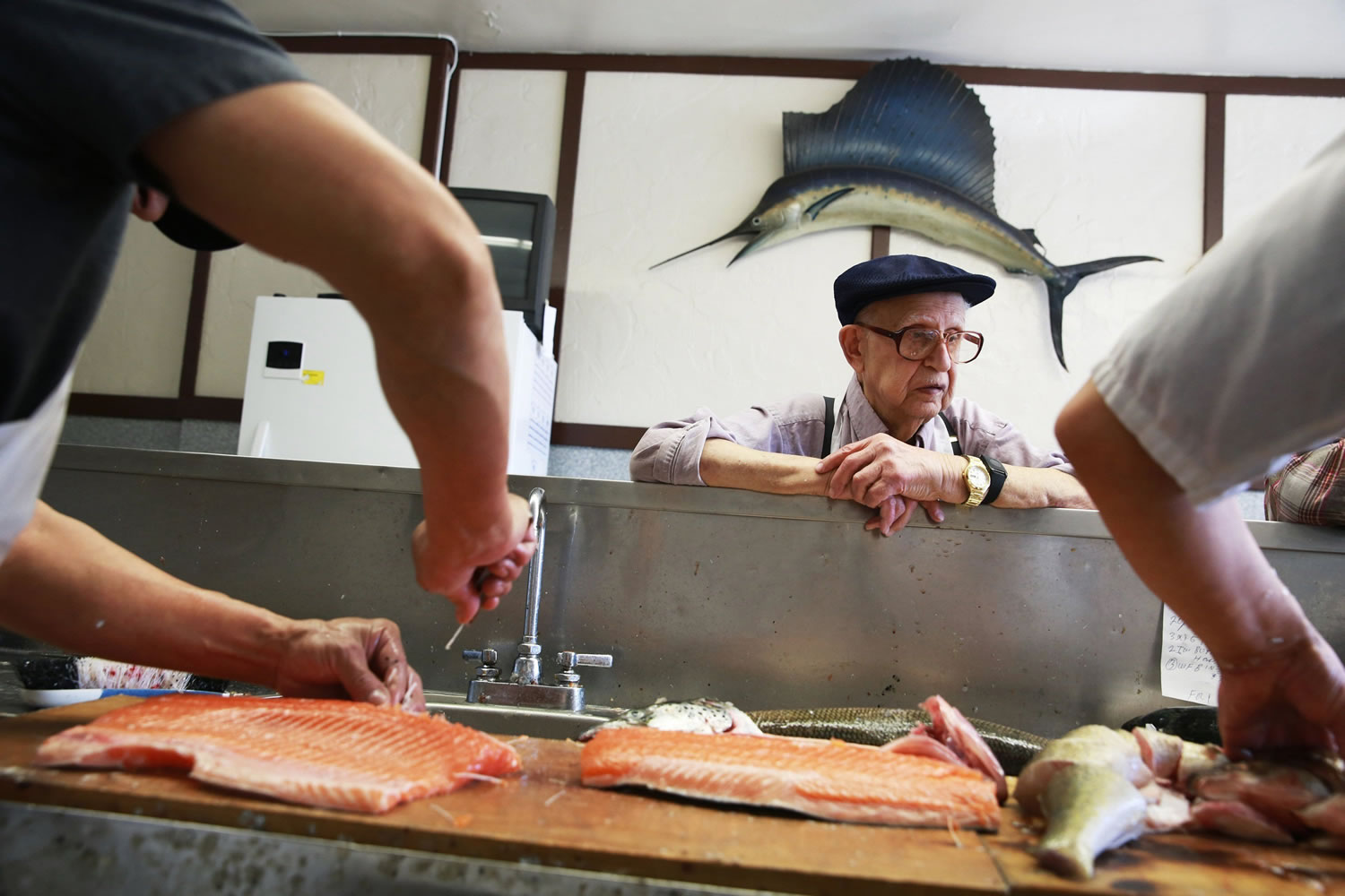 Robert's Fish Market worker Robert Schuffler, 97, watches Luis Fernandez, 58, left, and owner Arturo Venegas, 44, prepare fish at the fish market on West Devon Avenue in Chicago on Friday, April 11, 2014. Chicago-area fish suppliers are dealing with panicked cooks after a shortage of whitefish has left many scrambling to prepare the traditional, if  sometimes dreaded, gefilte fish for Passover, which begins Monday evening.