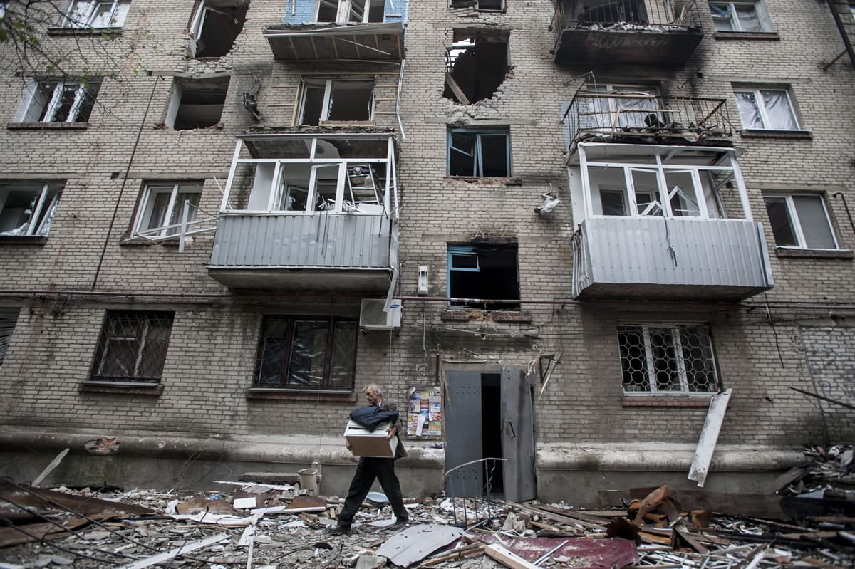 A man carries his belongings Thursday from an apartment building damaged by shelling in Slovyansk, eastern Ukraine.