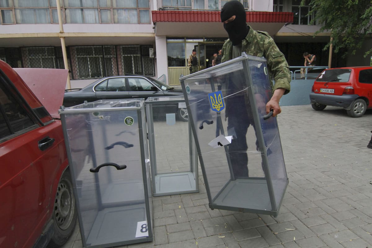 A Pro-Russian insurgent takes a ballot box away from a polling station Friday in Donetsk, Ukraine.