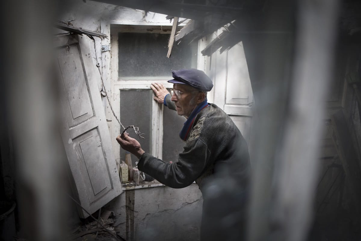 Viktor Melnikov, 76, an elderly local citizen,  looks the damage after a mine exploded near his house during an exchange fire between pro-Russian militants and government troops outside Slovyansk, eastern Ukraine, Thursday, May 15, 2014. The Organization for Security and Cooperation in Europe, a trans-Atlantic security group, put forward a &quot;road map&quot; calling for national dialogue as a first step toward resolving the escalating tensions.