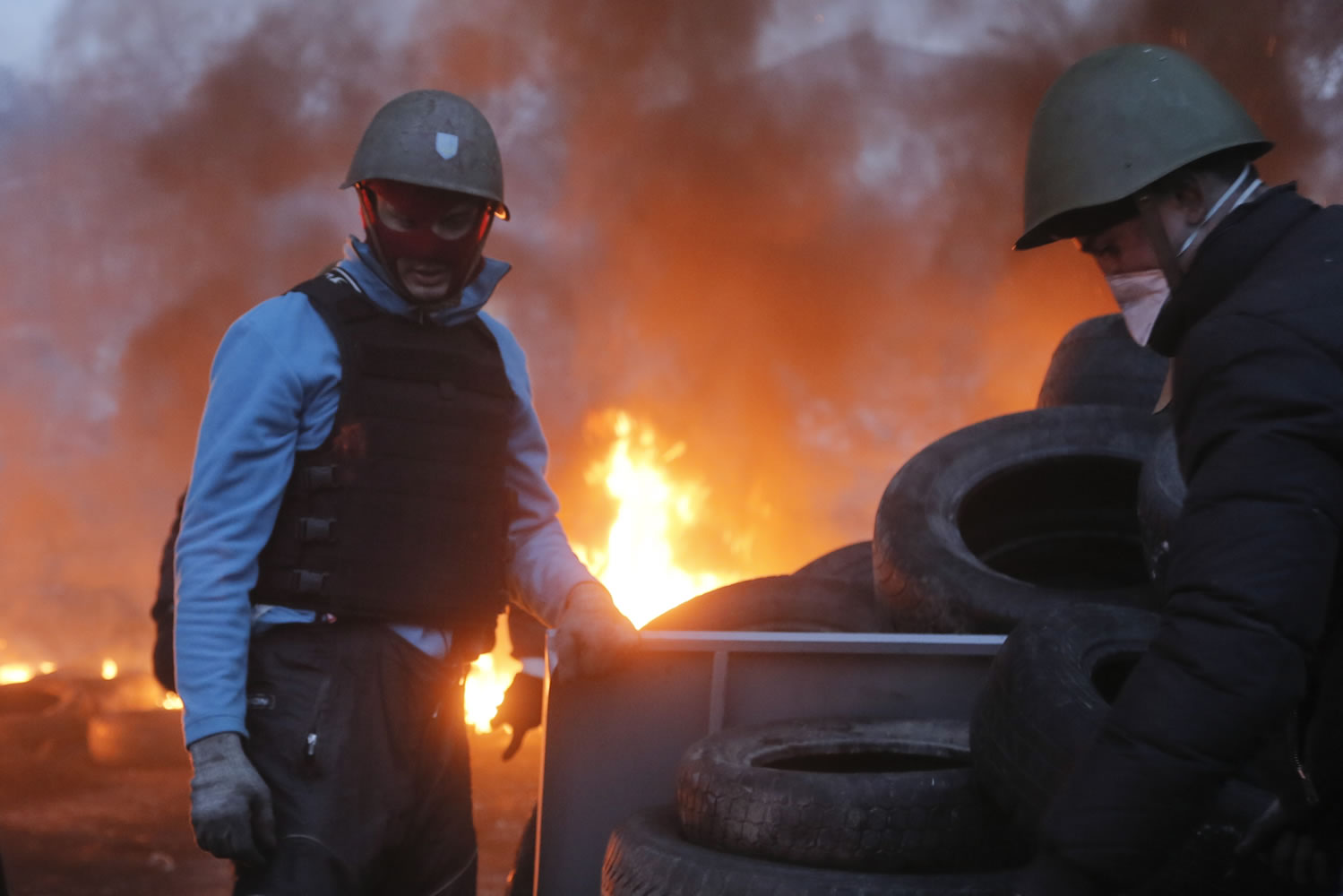 An activist carries a tire at the burning barricades, close to Independence Square, the epicenter of the country's current unrest, in Kiev, Ukraine, on Thursday.