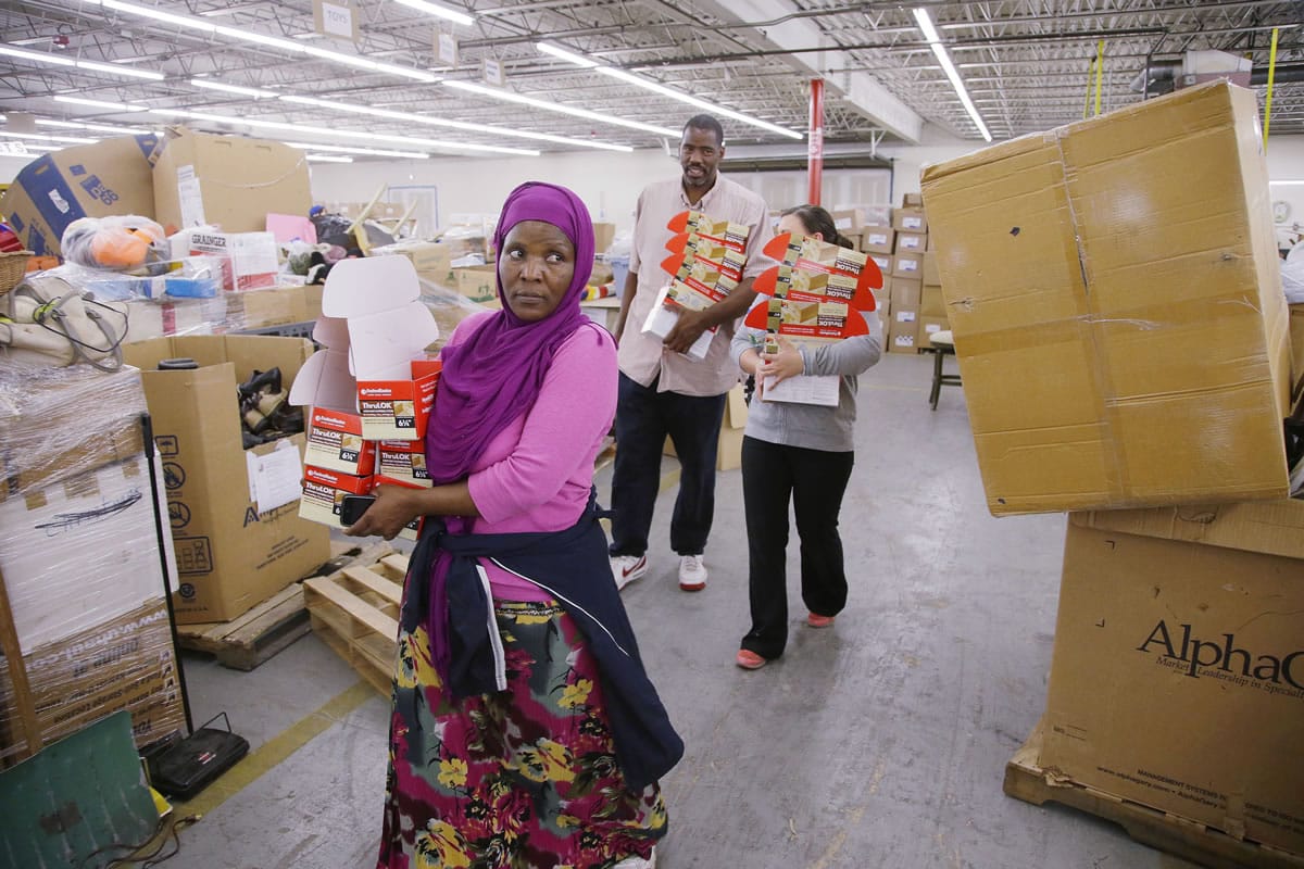 Somali refugee Madino Idoor, 35, carries boxes of merchandise she has put together during work at Pioneer Valley Goodwill Industries on June 17 in Springfield, Mass.