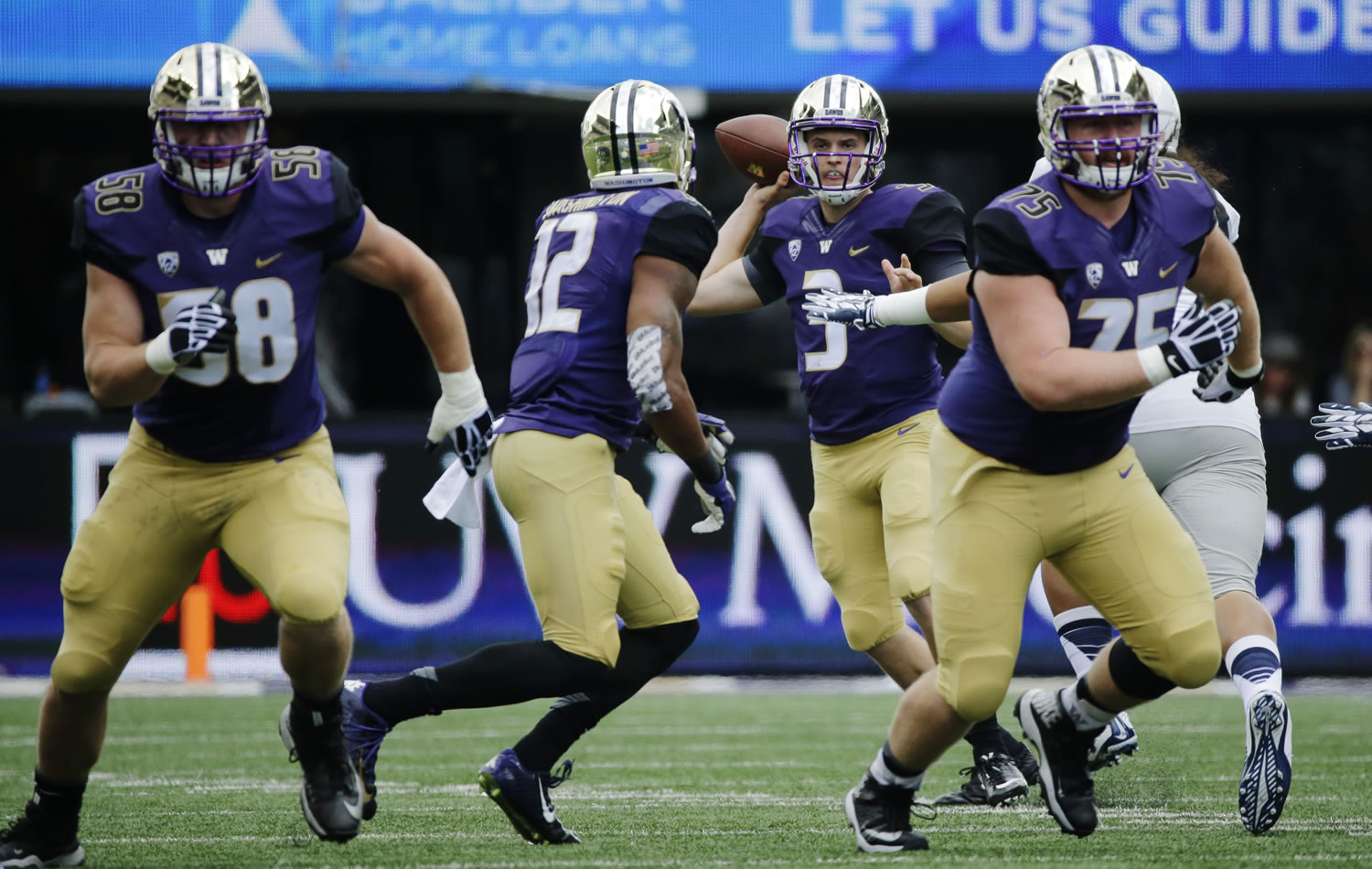 Washington quarterback Jake Browning (3) prepares to complete a pass to Dwayne Washington (12) as Jesse Sosebee, right, and Kaleb McGary, left, block against Utah State in the first half, Saturday, Sept. 19, 2015, in Seattle. (AP Photo/Ted S.