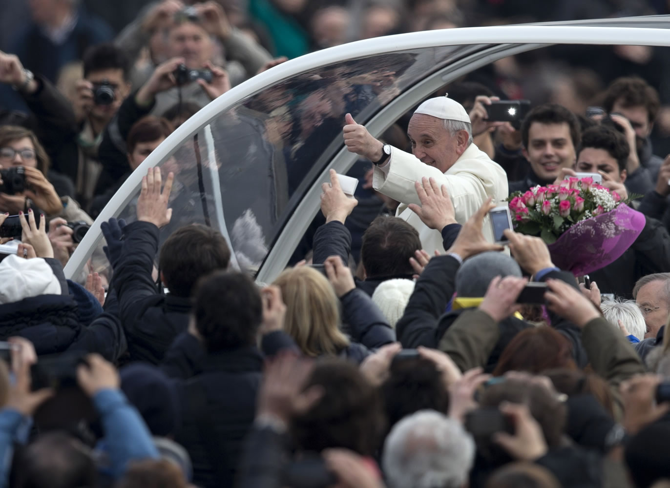 Pope Francis gives the thumbs up as he is driven through the crowd in his pope-moblie for for his weekly general audience in St.
