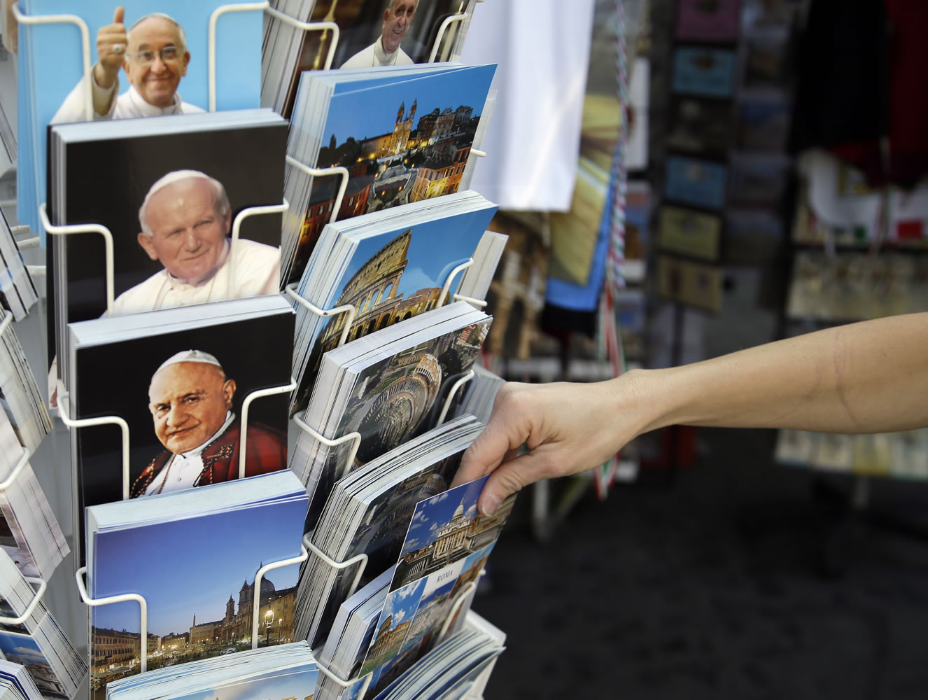 Postcards of pontiffs John XXIII, bottom left, John Paul II, center, and Pope Francis, top, are sold at a kiosk near the Vatican on Friday.
