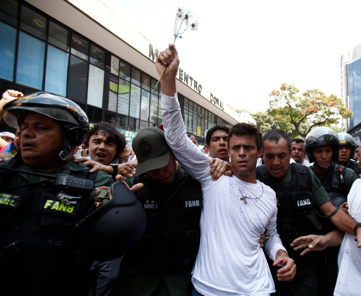 Opposition leader Leopoldo Lopez, holding up a flower, is taken into custody by Bolivarian National Guards on Tuesday in Caracas, Venezuela.