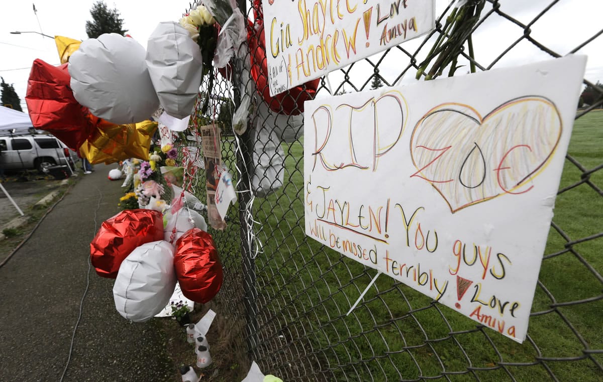 FILE - In this Oct. 27, 2014 file photo, a hand-written sign is attached to a fence at a growing memorial at Marysville Pilchuck High School in Marysville, Wash. The sign makes reference to Jaylen Fryberg, a freshman at the school who fatally shot four friends in the school cafeteria on Oct. 24, 2014 before killing himself. A report released Tuesday, Sept. 1, 2015 said that Fryberg's motive remains unclear, but that he sent a group text message to his family outlining his funeral wishes and apologizing to the parents of the teenagers he was about to kill. (AP Photo/Ted S.