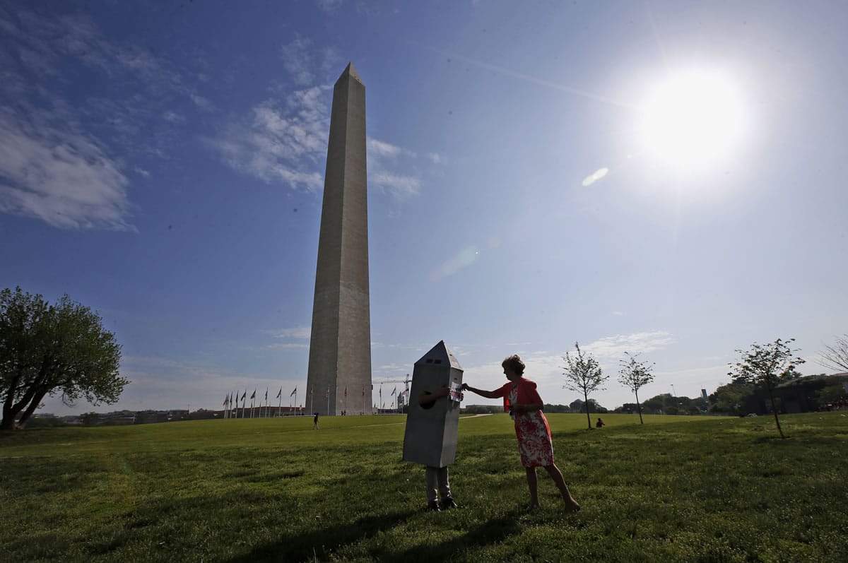 Vicki Dixon, an Interior Department employee, right, helps her colleague Steven Avila, with his Washington Monument costume at the Washington Monument in Washington on Monday, ahead of a ceremony to celebrate its re-opening.