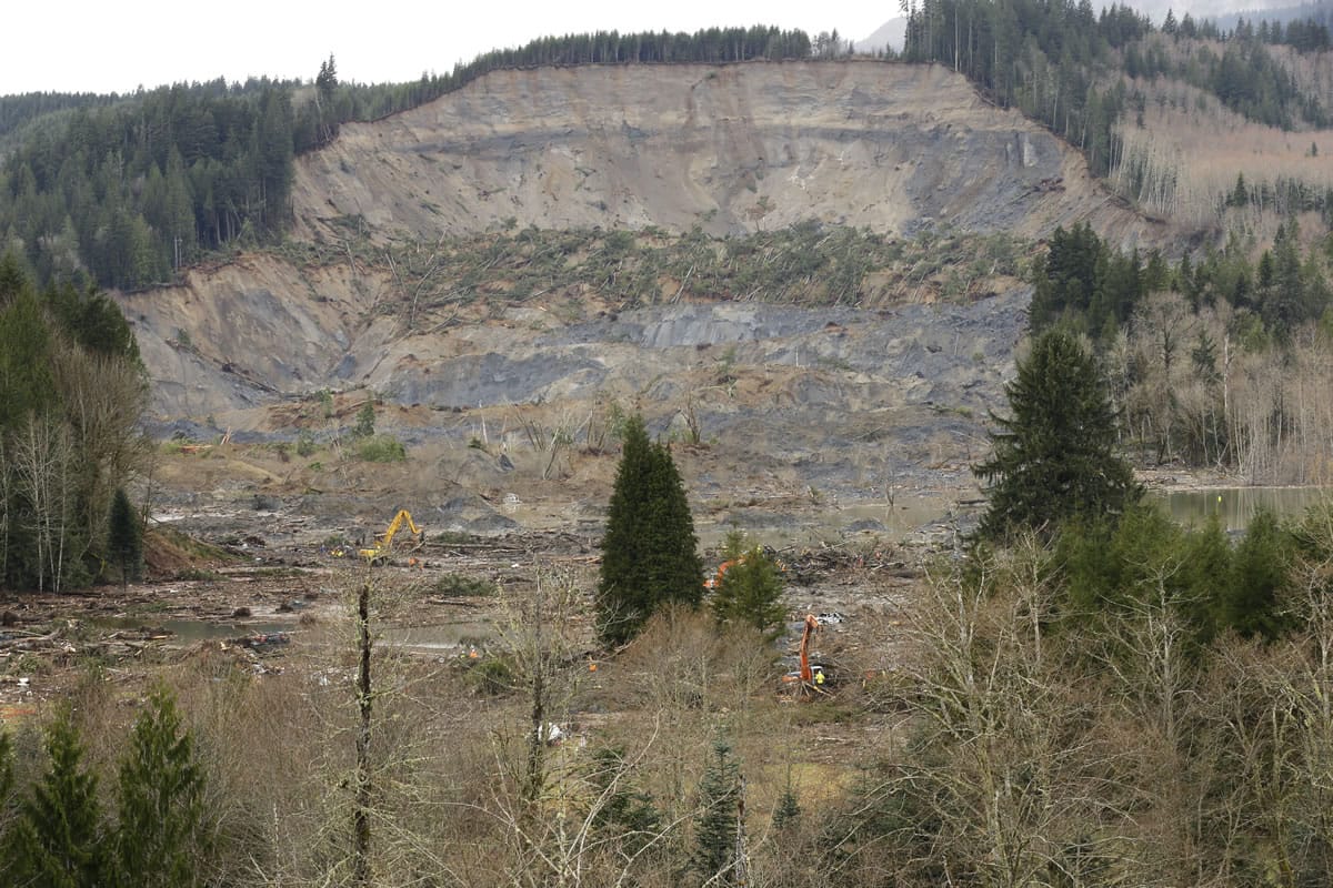 The scene of the massive deadly mudslide that hit the community of Oso on March 22 is shown Sunday with heavy equipment working to clear trees and debris, near Darrington, as the search for victims continues.
