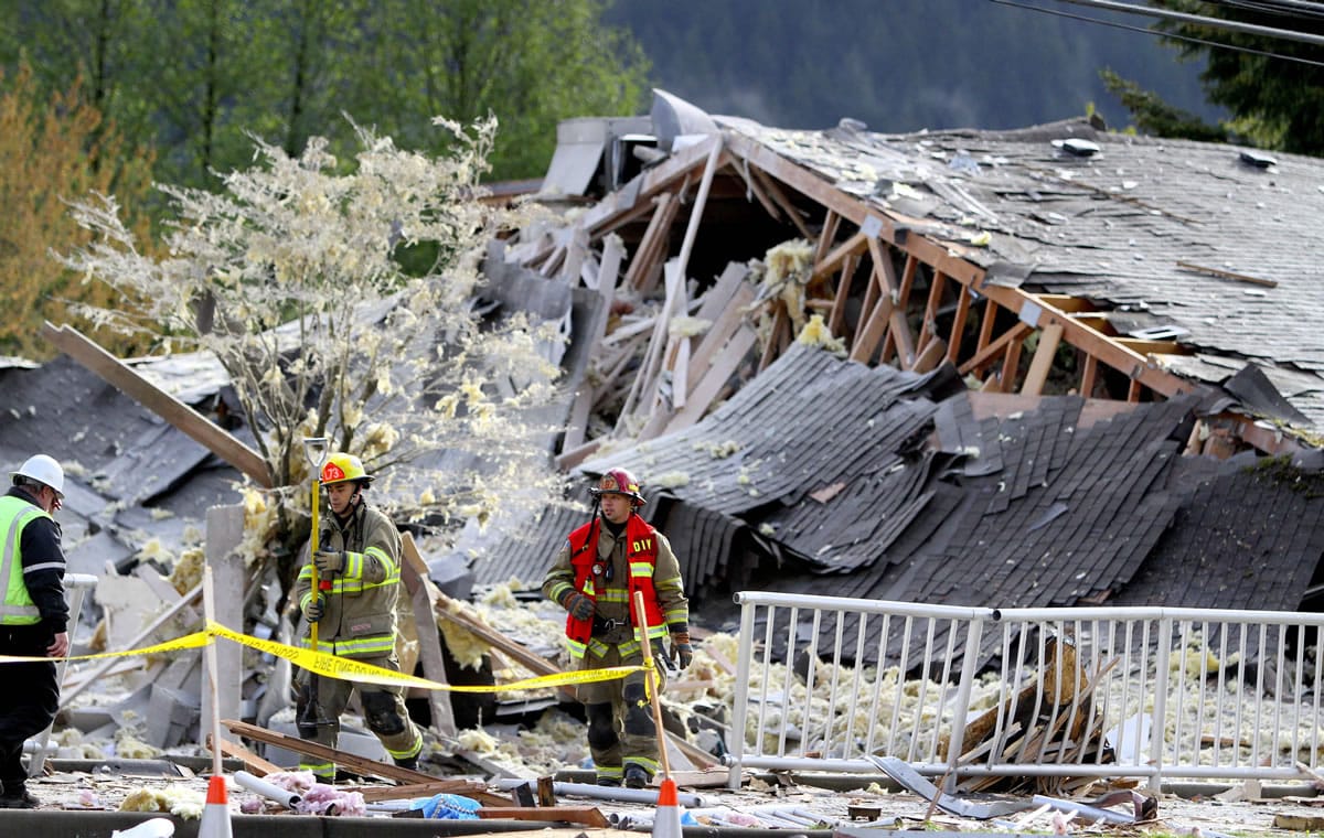 Firefighters and work crews survey the damage of a large explosion in North Bend on Friday.