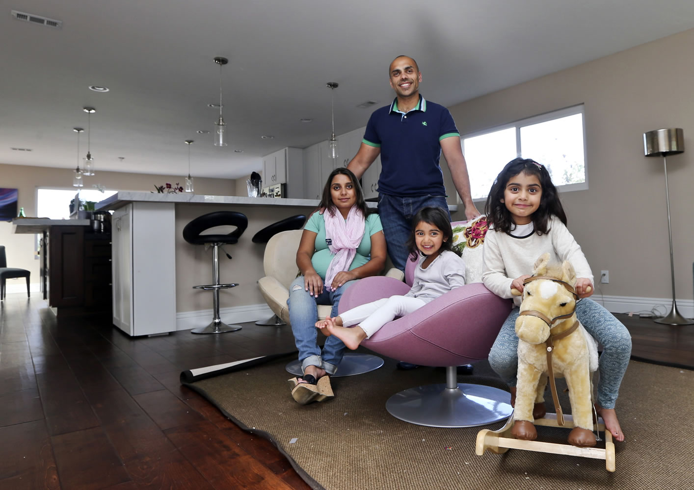 The Jaswal family, Imran, standing, his wife Aniqa, left, and daughters, Arissa, right, and Jayda, gather in the family room at their home in La Jolla, Calif. The couple bought the four-bedroom house about 10 minutes from the beach in Febrauary.