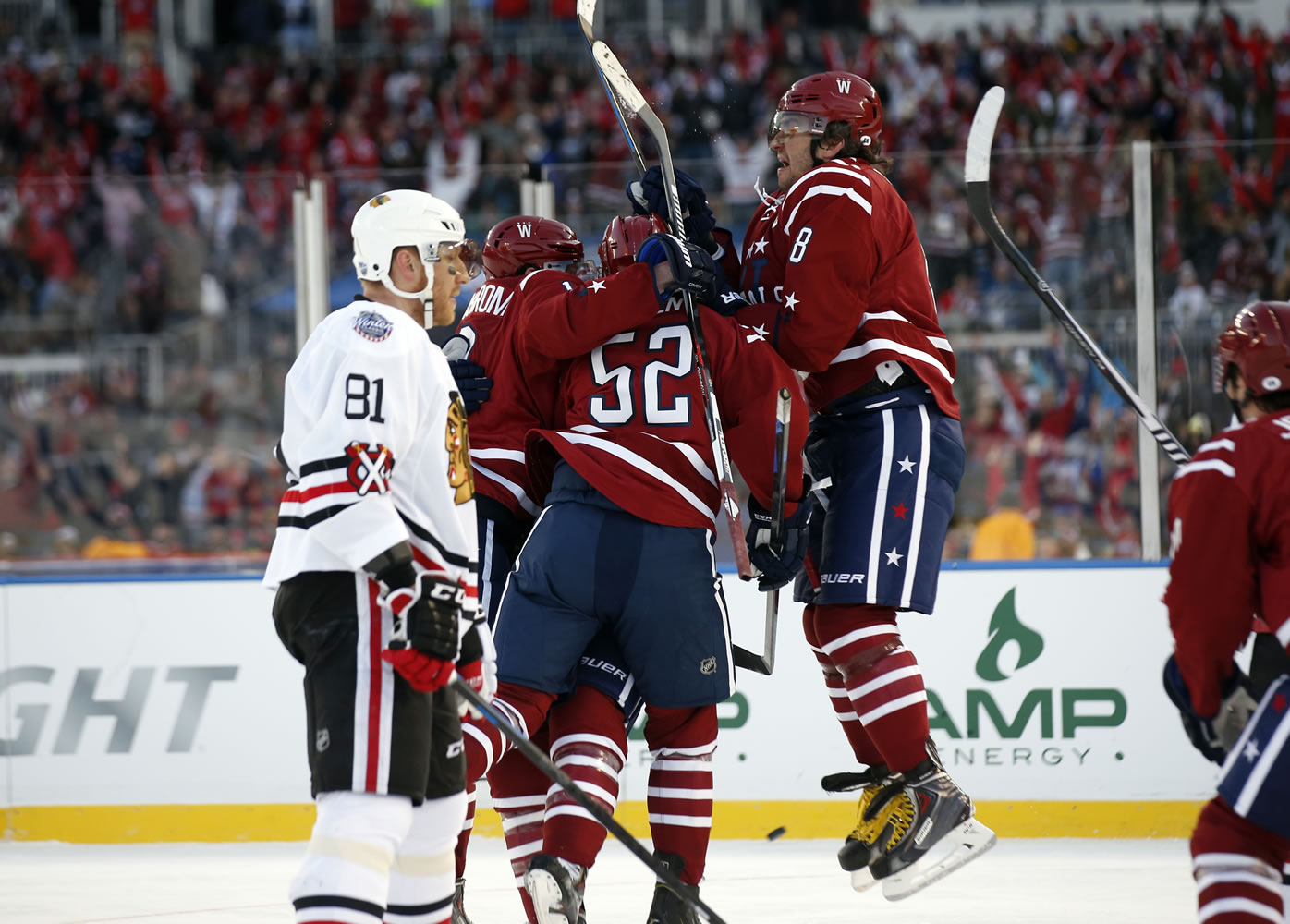 Washington's Nicklas Backstrom, Mike Green (52) and Alex Ovechkin (8) surround Troy Brouwer after Brouwer scored the winning goal as Chicago Blackhawks right wing Marian Hossa (81) looks on in the closing seconds of the third period of the Winter Classic at Nationals Park on Thursday, Jan. 1, 2015, in Washington. The Capitals won 3-2.