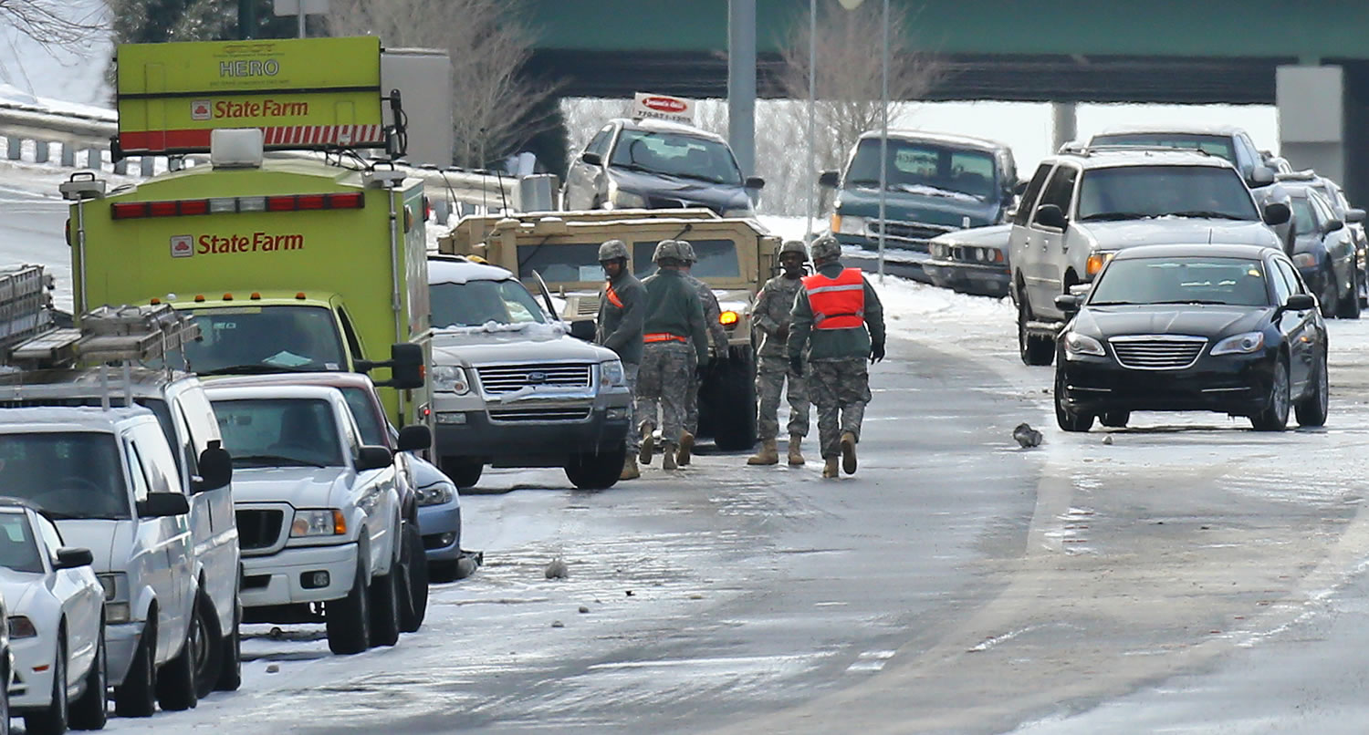 Georgia National Guard troops in humvees and a HERO unit check on a stranded motorists and search abandoned vehicles to give aid to those still stuck on the highway at Roswell Road and I-285 on Wednesday afternoon,, more than 24 hours after a storm hit in Atlanta.