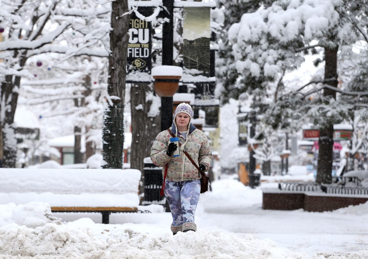 Alexa Hight of Longmont takes a stroll on the Pearl St. Mall after showing up too early for work, amid fresh snow in Boulder, Colo., Friday, Dec. 26, 2014. Parts of Colorado's mountains and plains are getting more snow, but the Christmas storm is tapering off in the Denver area.