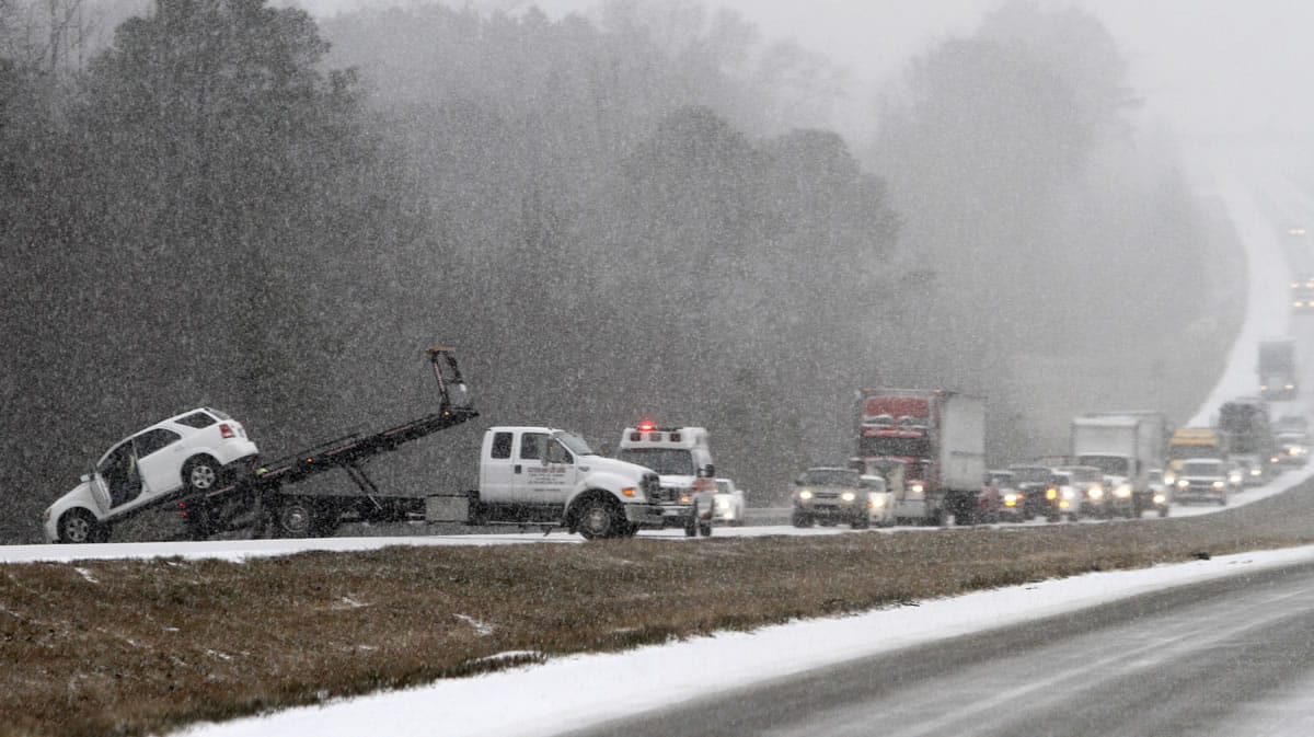 Traffic backs up as a wrecker pulls a car out of a ditch on I-65 during an unusual snow Tuesday in Clanton, Ala.