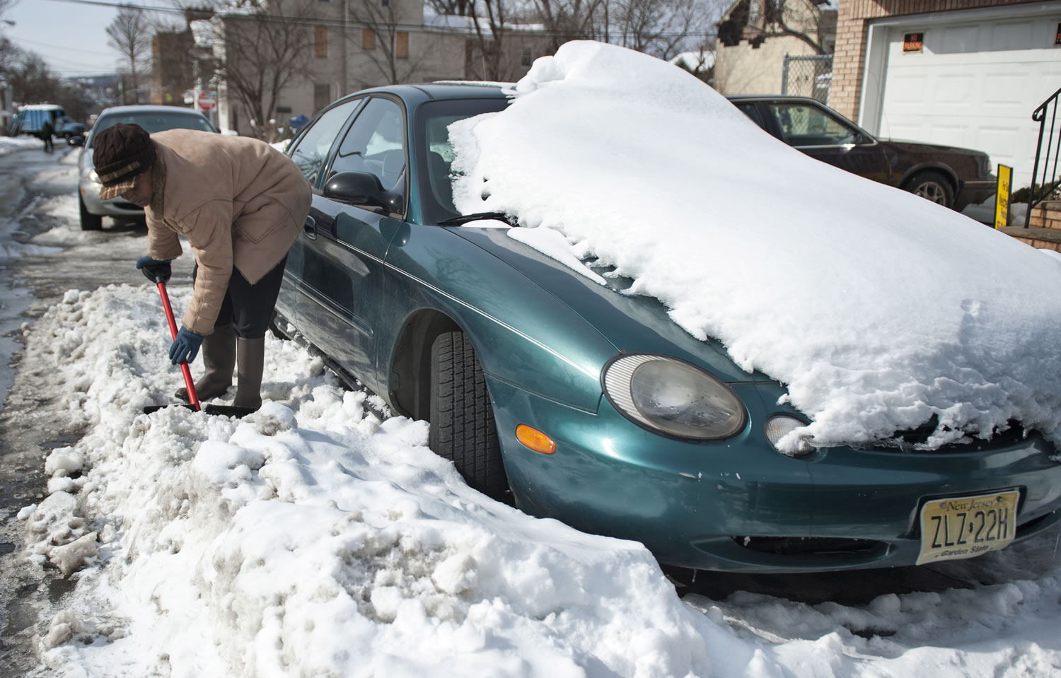 Ingrid Parham chisels away at snow surrounding her car Sunday in Paterson, N.J., in preparation for work today.