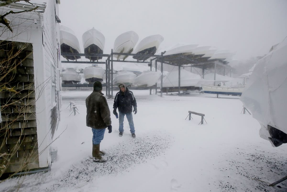 Alan Cohen, left, owner of the Ryder's Cove Marina talks with an employee, Ken Maynard, as they check on the state of the marina and the boats wintered there as high tide approaches in Chatham, Mass., on Wednesday.