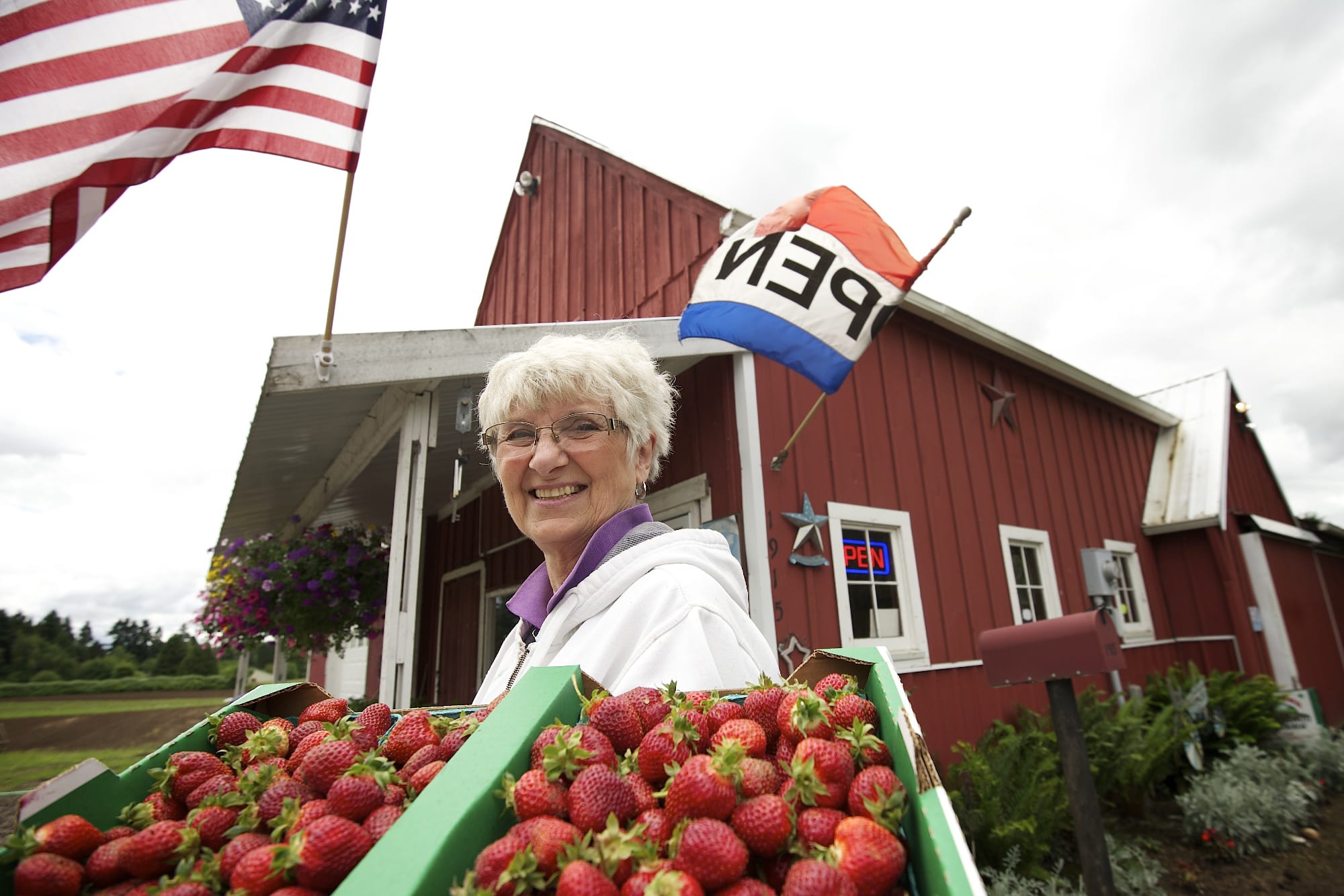 Carol Hoffman, owner of Red Barn, holds a flat of Hood strawberries outside her business in May in Vancouver. &quot;The customers prefer the Hood flavor,&quot; said Hoffman.