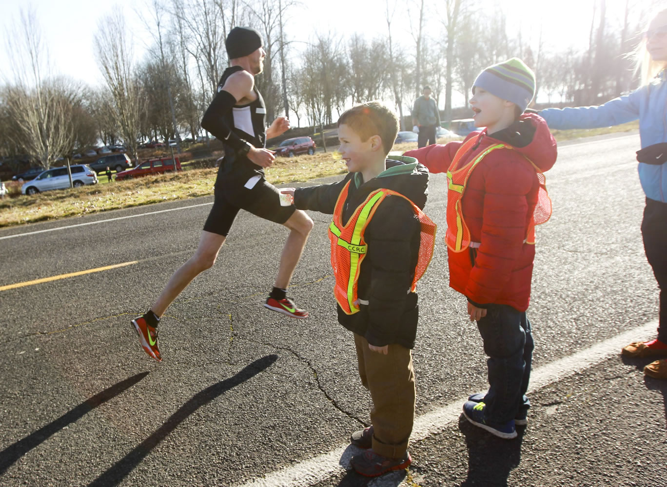 Volunteers offer water to runner Johnson Lee as he passes in the annual Vancouver Lake Half Marathon on Sunday.