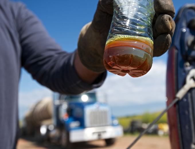 Truck driver Christopher Piche of Battle Ground shows a bottle containing crude from the Bakken oil fields at his home in Watford City, N.D., on Aug.