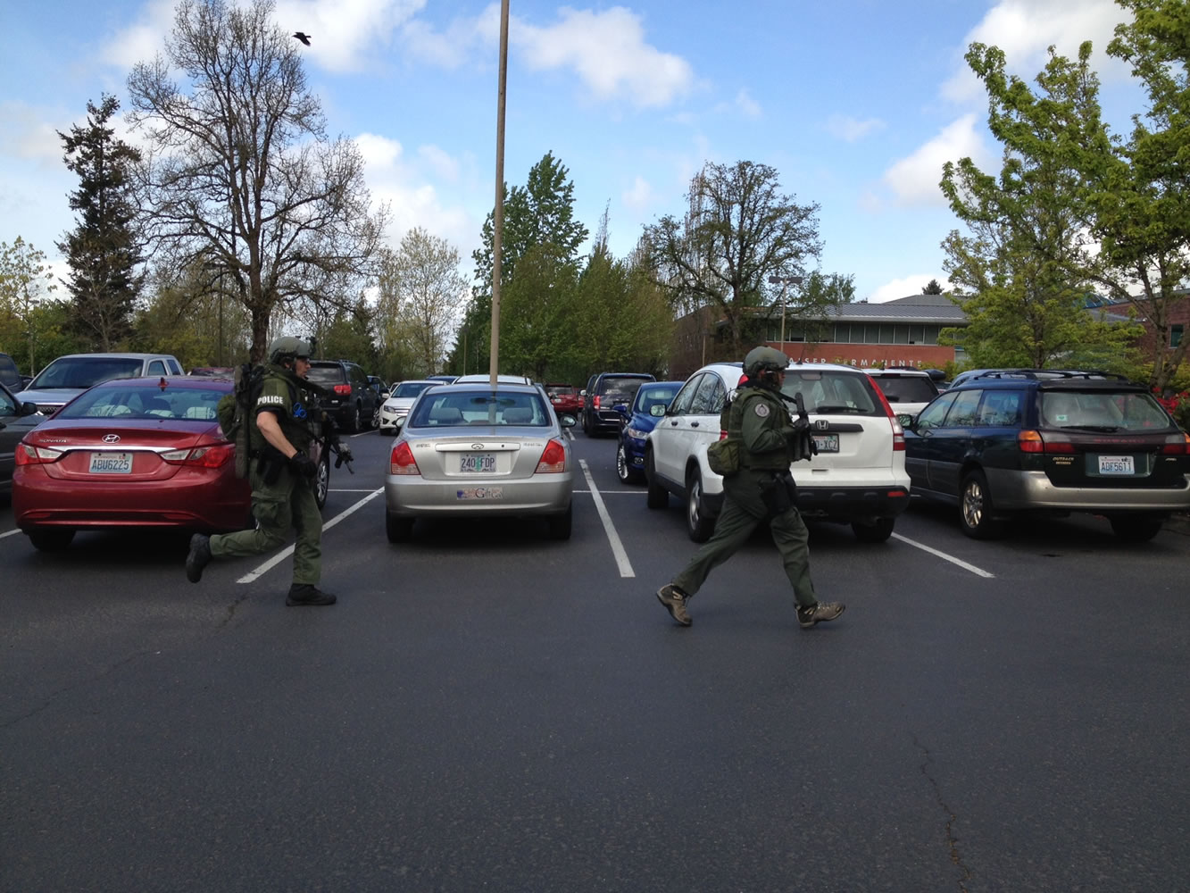 Heavily-armed police officers run toward the University Plaza building, just north of Kaiser Permanente's Salmon Creek Medical Office, after a man with reported mental health conditions brought a firearm into a mental health clinic.