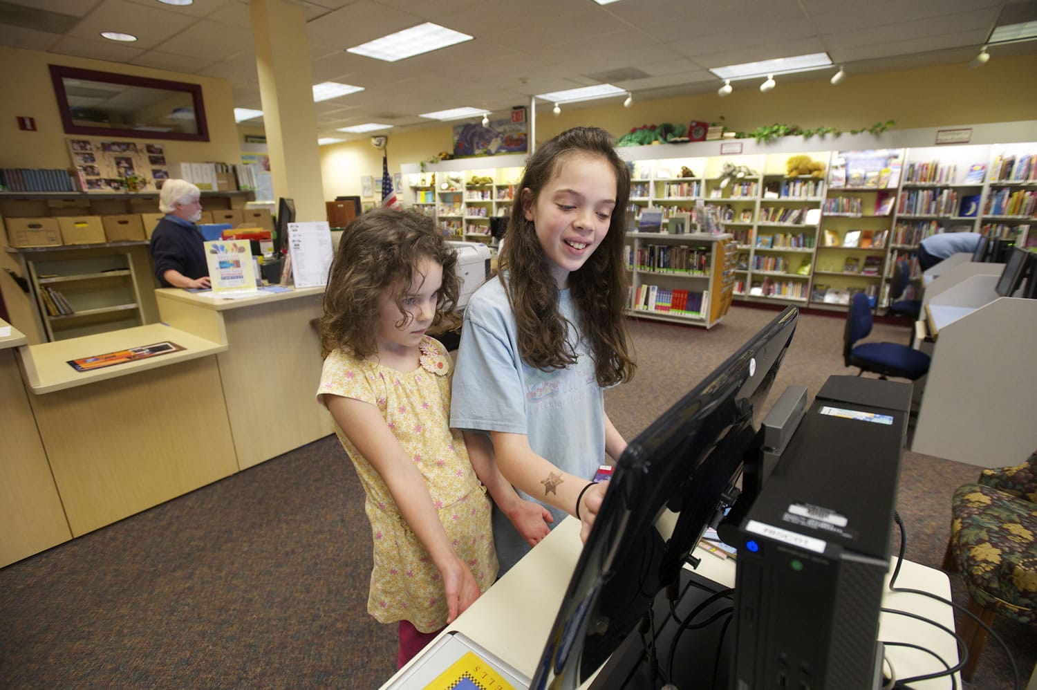 Aviela Olson, 5, left, and her sister Madeleine Olson, 10, check out books at the Ridgefield library on March 14.