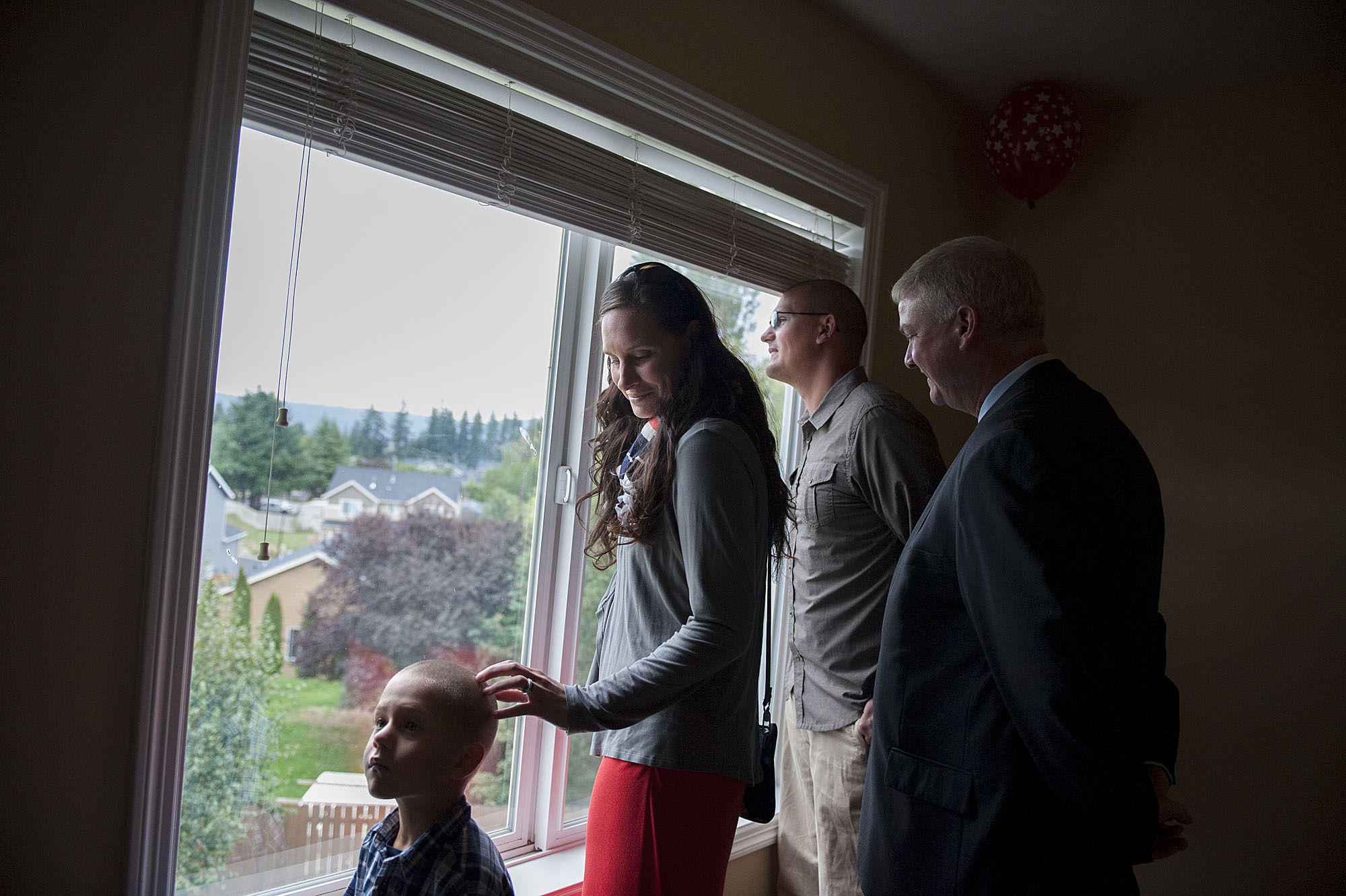 Staff Sgt. Corey Collins, second from right, checks out the view from a window on the second floor of his new Washougal home with his son, Liam, 5, and his wife, Katie, and Thomas Kilgannon, president of Freedom Alliance.