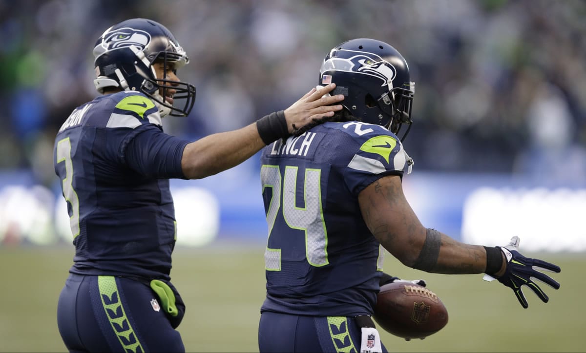 Seattle Seahawks running back Marshawn Lynch, right, gets a pat on the back from quarterback Russell Wilson as he goes to shake the hand of another teammate after scoring a touchdown against St. Louis Rams on Dec.