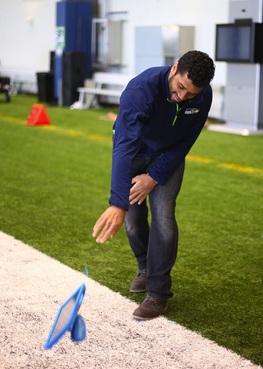 Seattle Seahawks quarterback Russell Wilson demonstrates the durability of the Microsoft Surface tablet that is specially modified for use by NFL teams on Dec. 16.