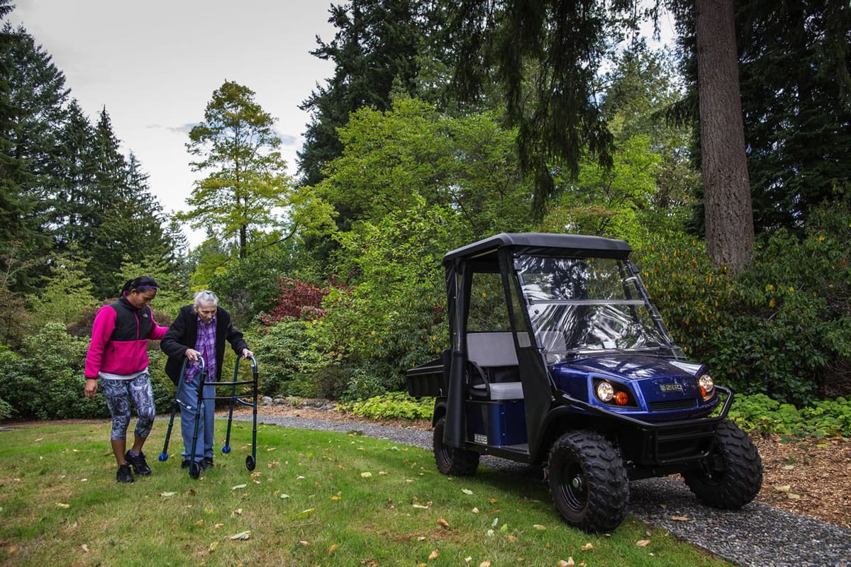 An electric golf cart gets Fir Butler around on her 6-acre property, with some help from caregiver Jessie Canfield. Fir Butler and her late husband, Merlin, donated the property to Snohomish County in the hopes it would be maintained as an arboretum after her death.