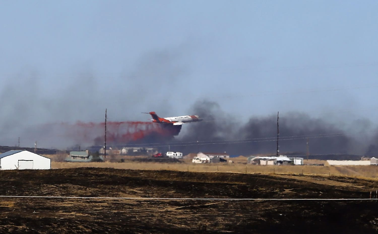 A plane helps in the effort to stop the spread of a wildfire Monday east of Evansville, Wyo.
